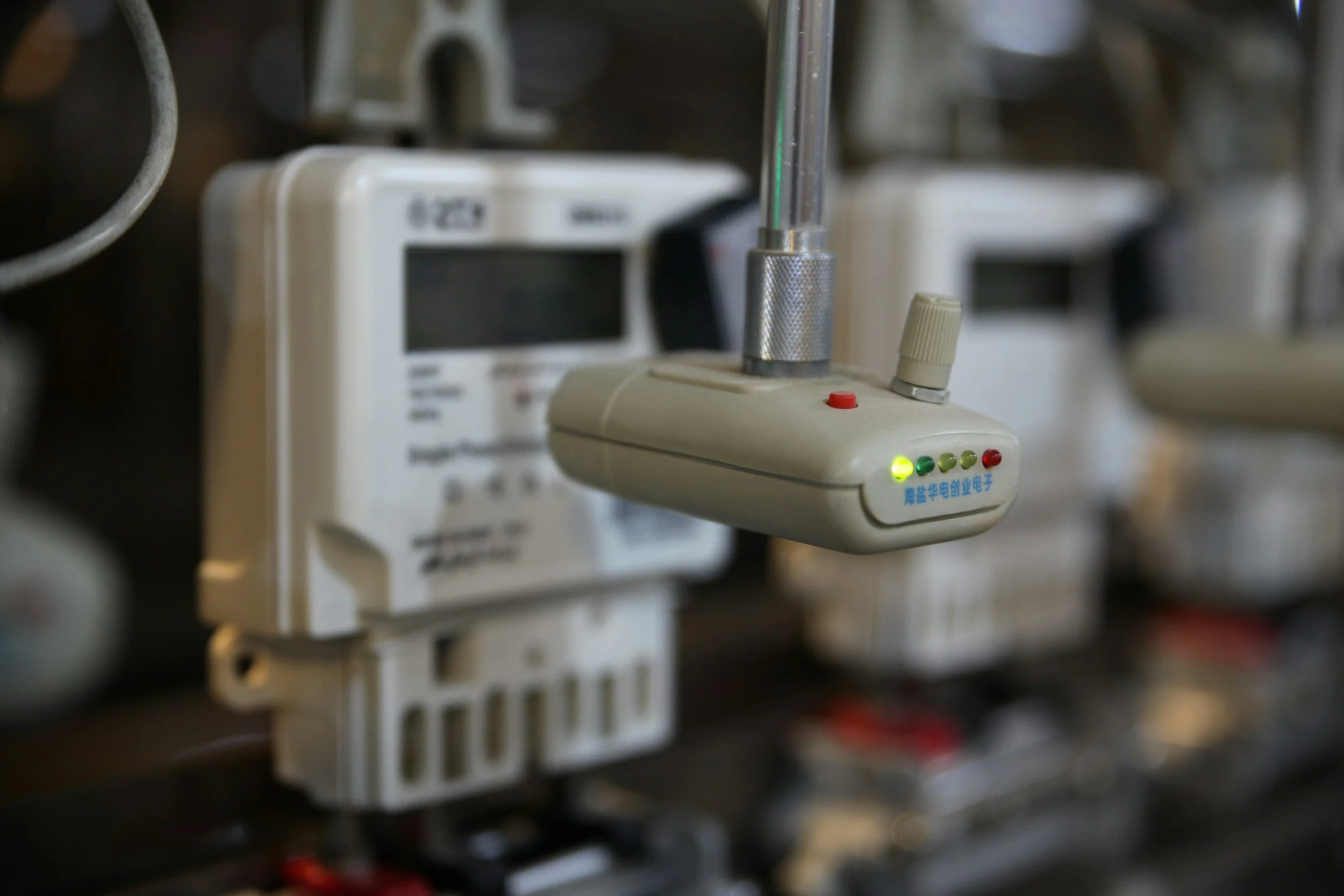 Close-up of an electrical device with indicator lights and a wireless antenna, mounted on a wall with similar units around it.