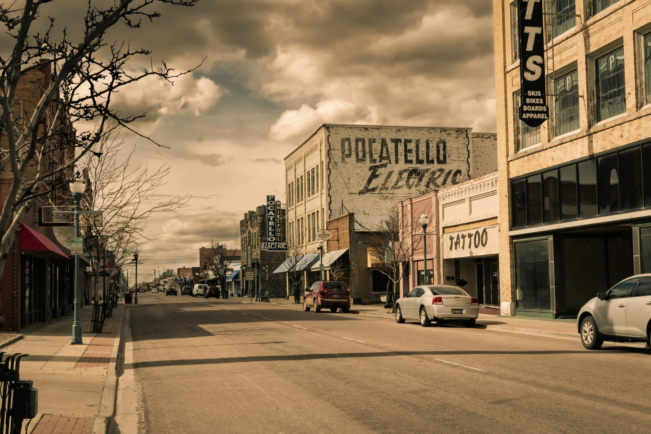 Historic downtown Pocatello, Idaho, main street with brick and stone commercial buildings, a painted Pocatello Electric wall sign, and storefronts under a cloudy sky