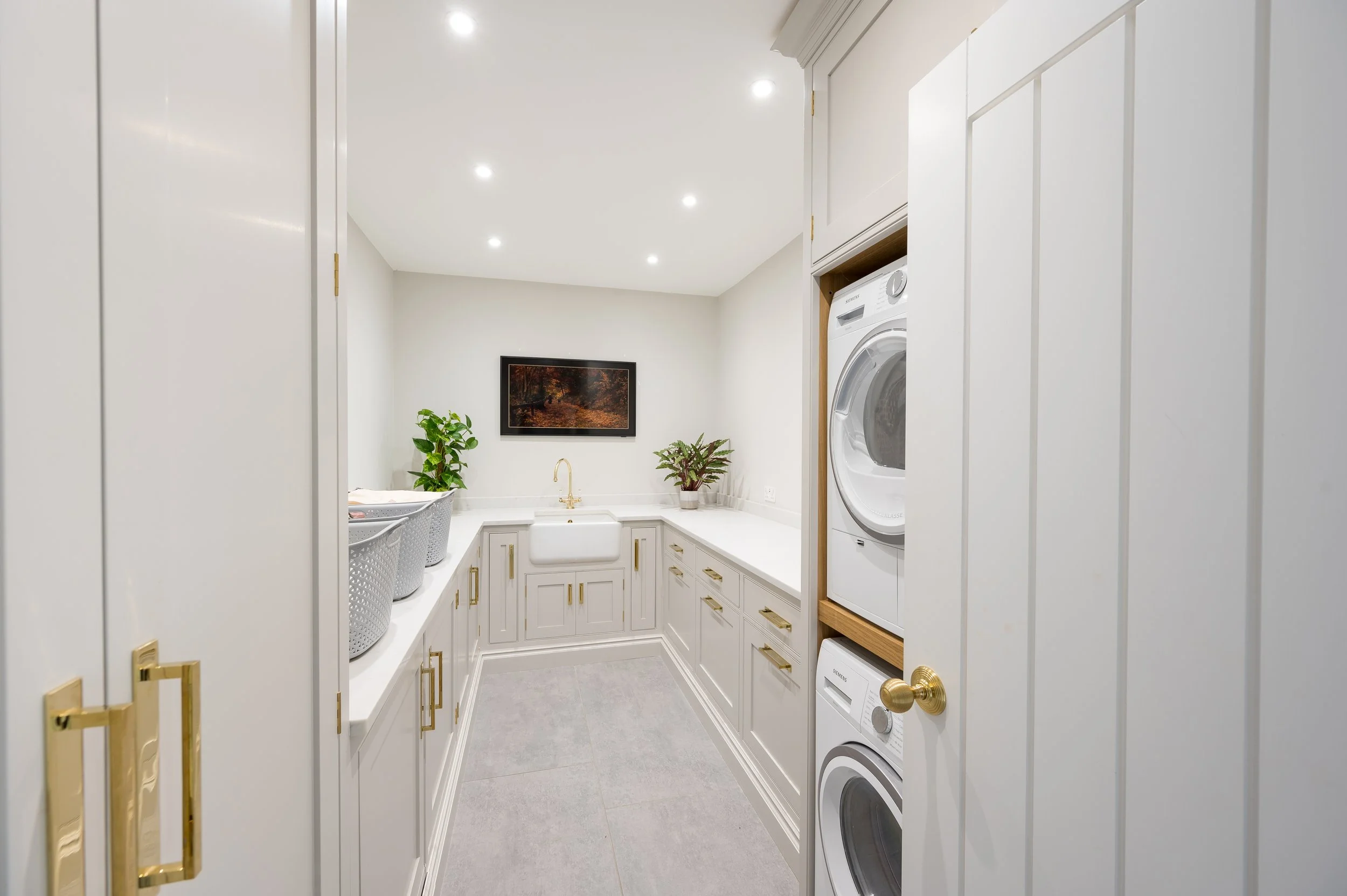Cream painted laundry room with tumble dryer and washing machine built into cabinetry 