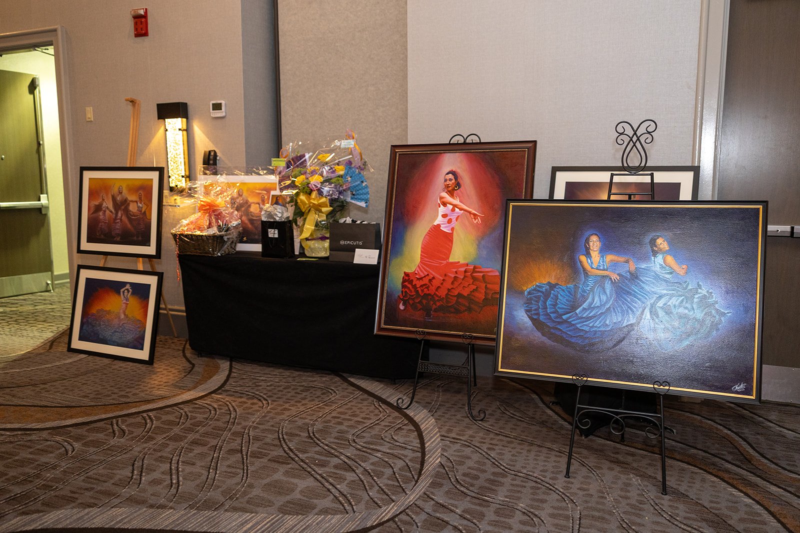 Paintings and floral arrangements on display in a gallery or event space.