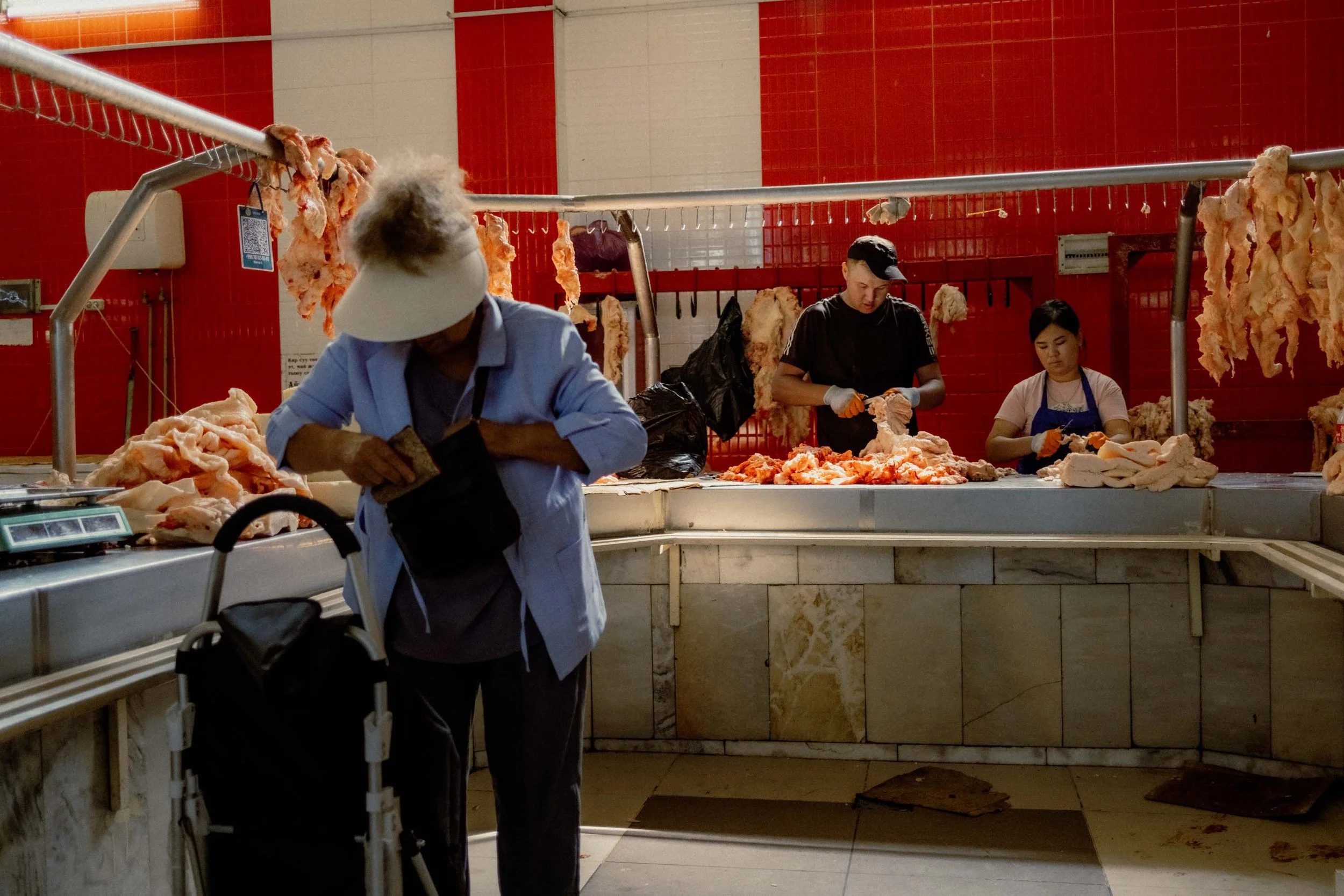 An authentic scene inside a red-toned butcher shop at the bustling Osh Bazaar in Bishkek, Kyrgyzstan.