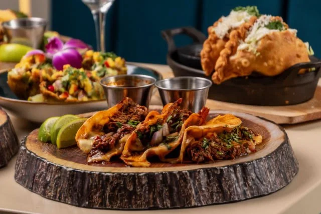 Best Latin food in Toronto platter with tacos, lime wedges, a side salad, and fried chicken with shredded lettuce on top.