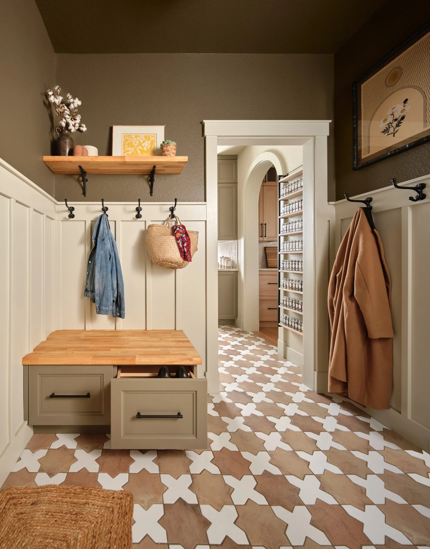 Mudroom with creamy paneling, olive upper walls, a butcher block bench and the opening to the pantry