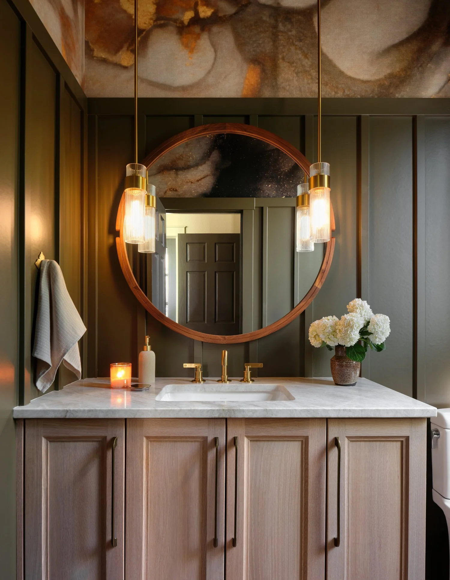White oak vanity, round wood mirror and fluted glass pendants under the cloud mural
