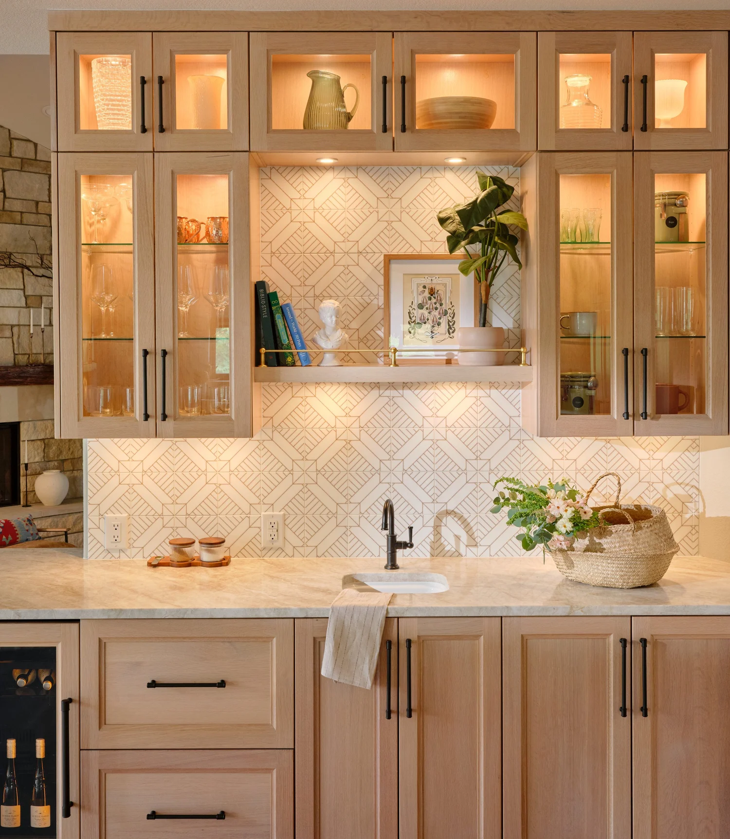 Lit glass front cabinets and the brass railed shelf over the printed marble backsplash