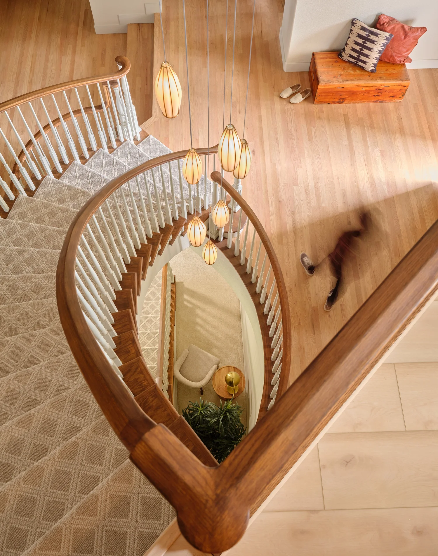 Looking down the curved staircase to the basement through the glowing pendant cluster