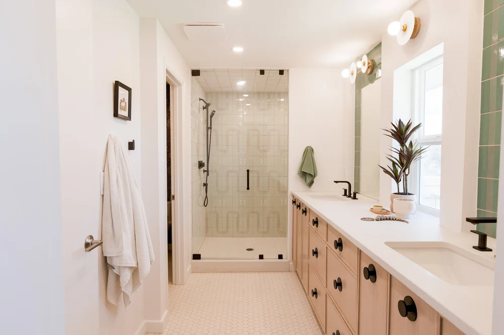 The 2023 primary suite at Pomona Lake, a double vanity with green tile and a walk in shower