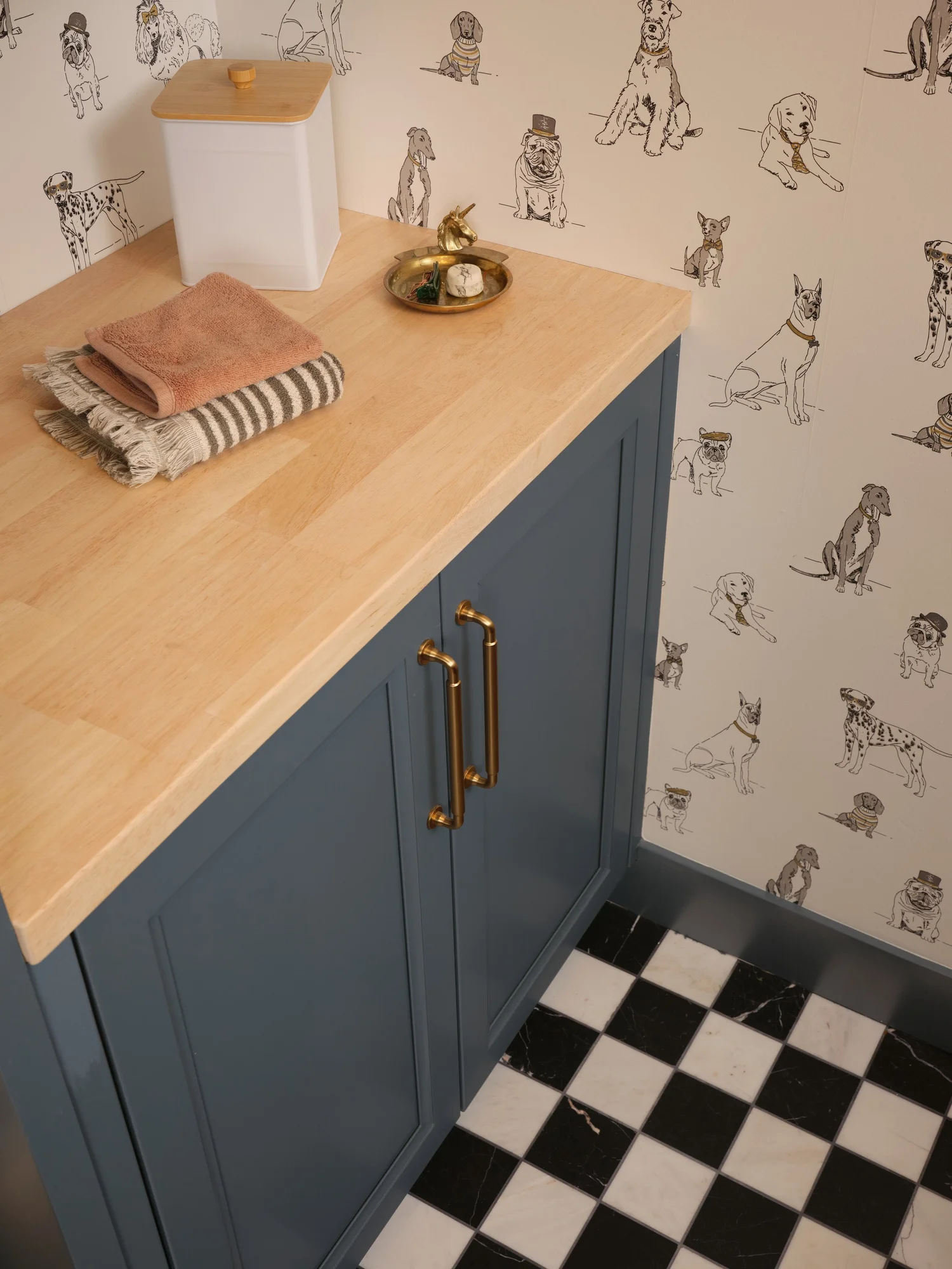 Brass pulls on blue cabinetry over the black and white marble floor