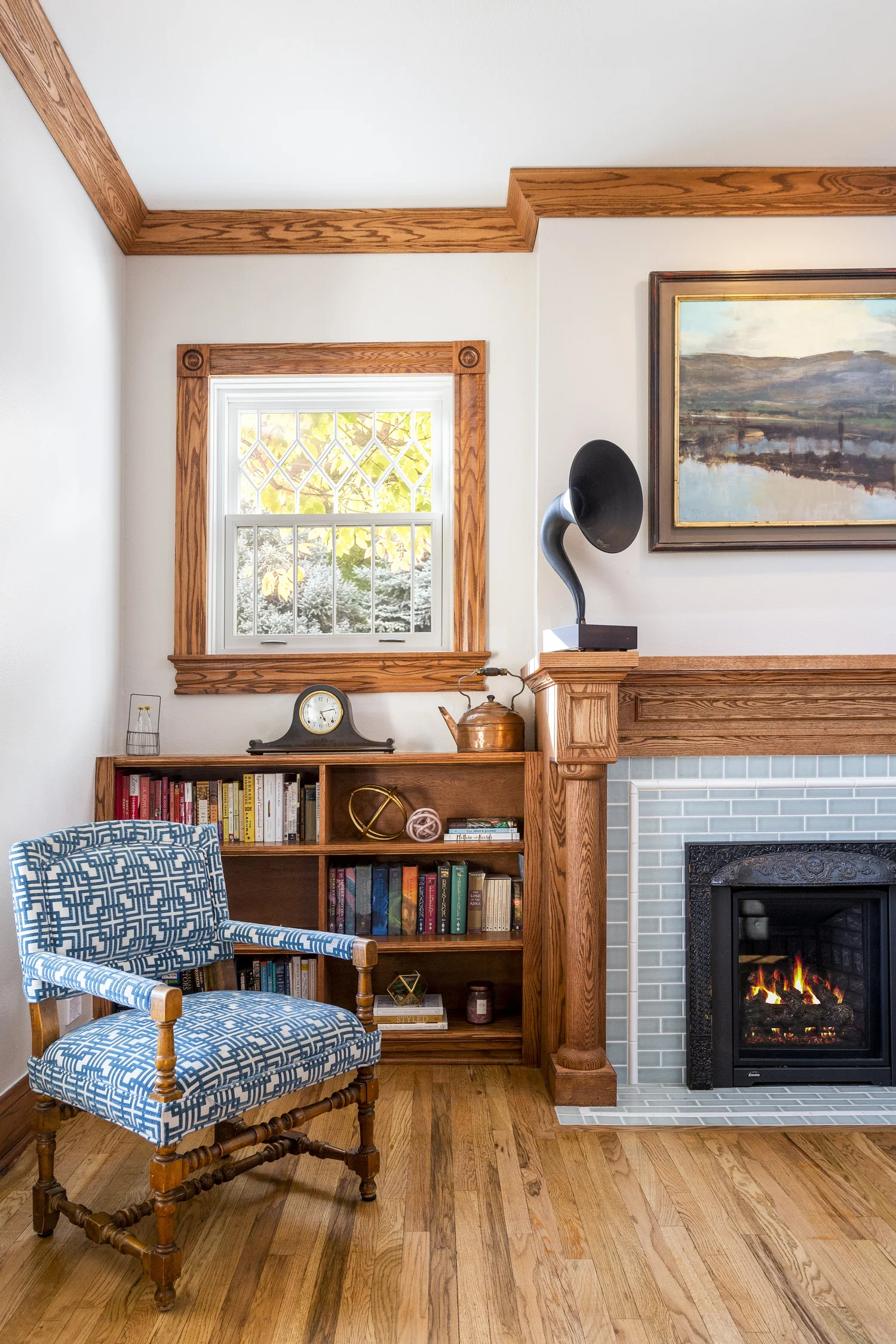 Living room in a historic Denver four square with original oak window trim and a wood fireplace mantel with a blue tile surround