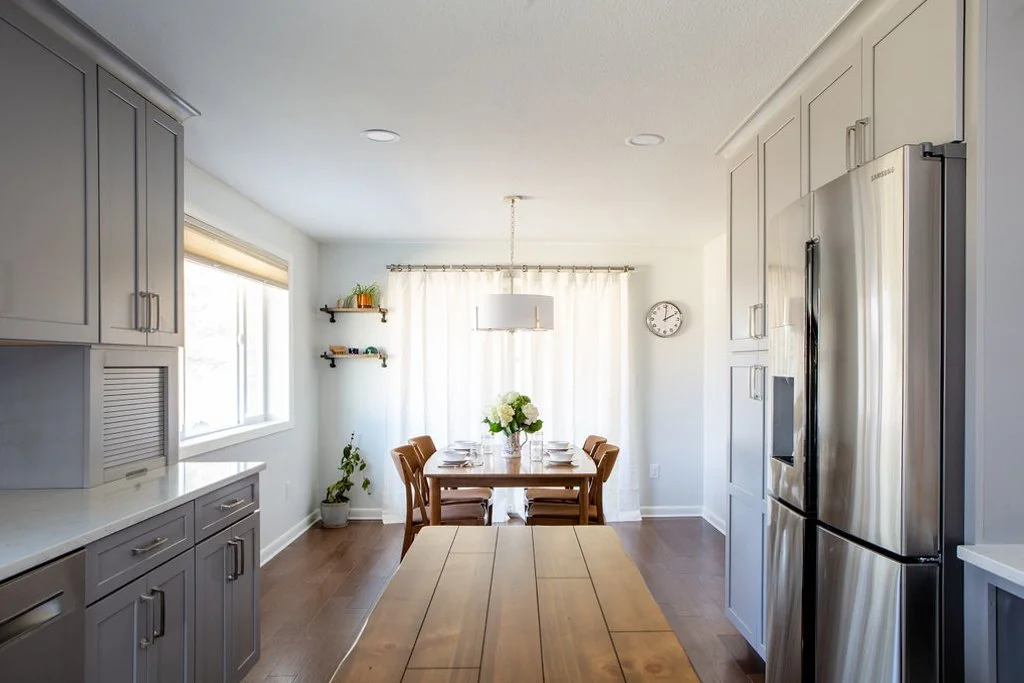 Remodeled kitchen in a Lakewood ranch home with soft grey shaker cabinets, white quartz countertops, and wood flooring running straight through to the dining table