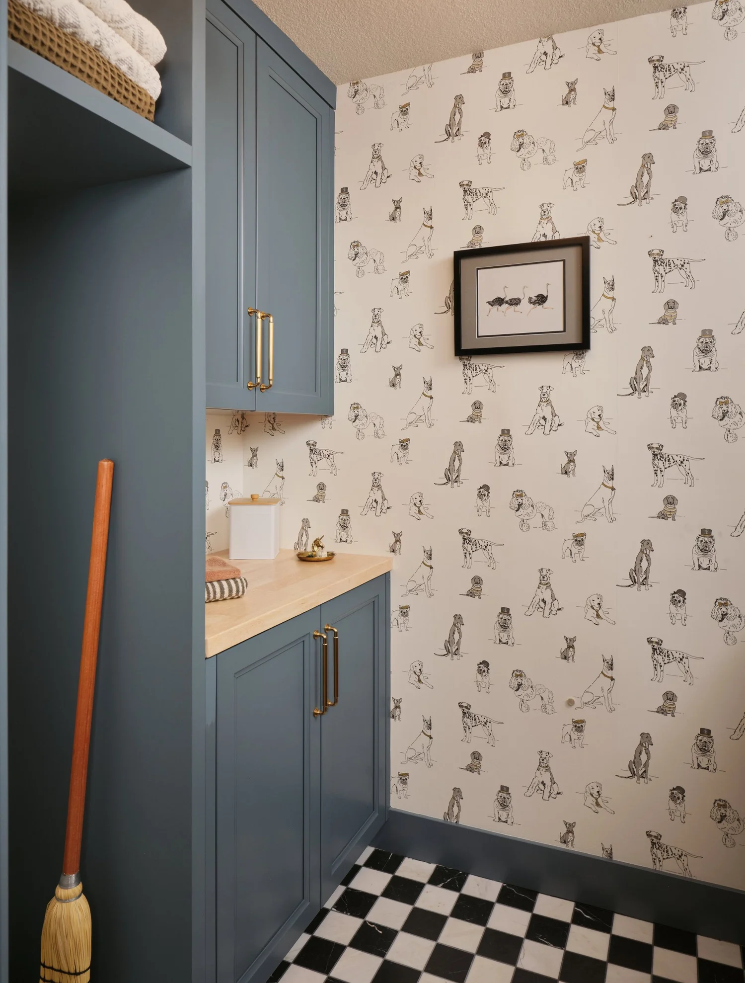Laundry with blue cabinetry, brass pulls, dog wallpaper and a marble checkerboard floor