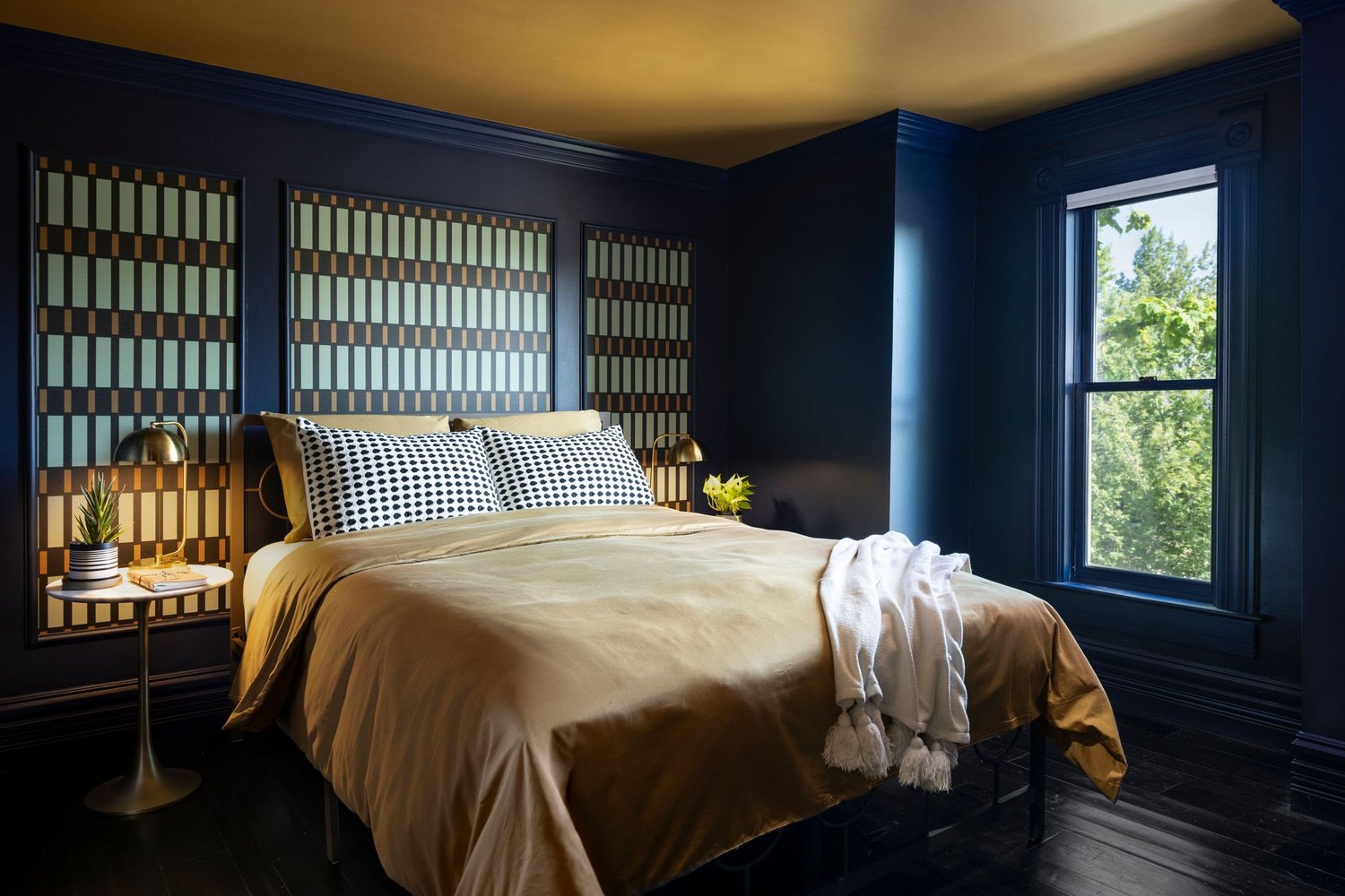 Guest bedroom after renovation with navy walls and a camel painted ceiling