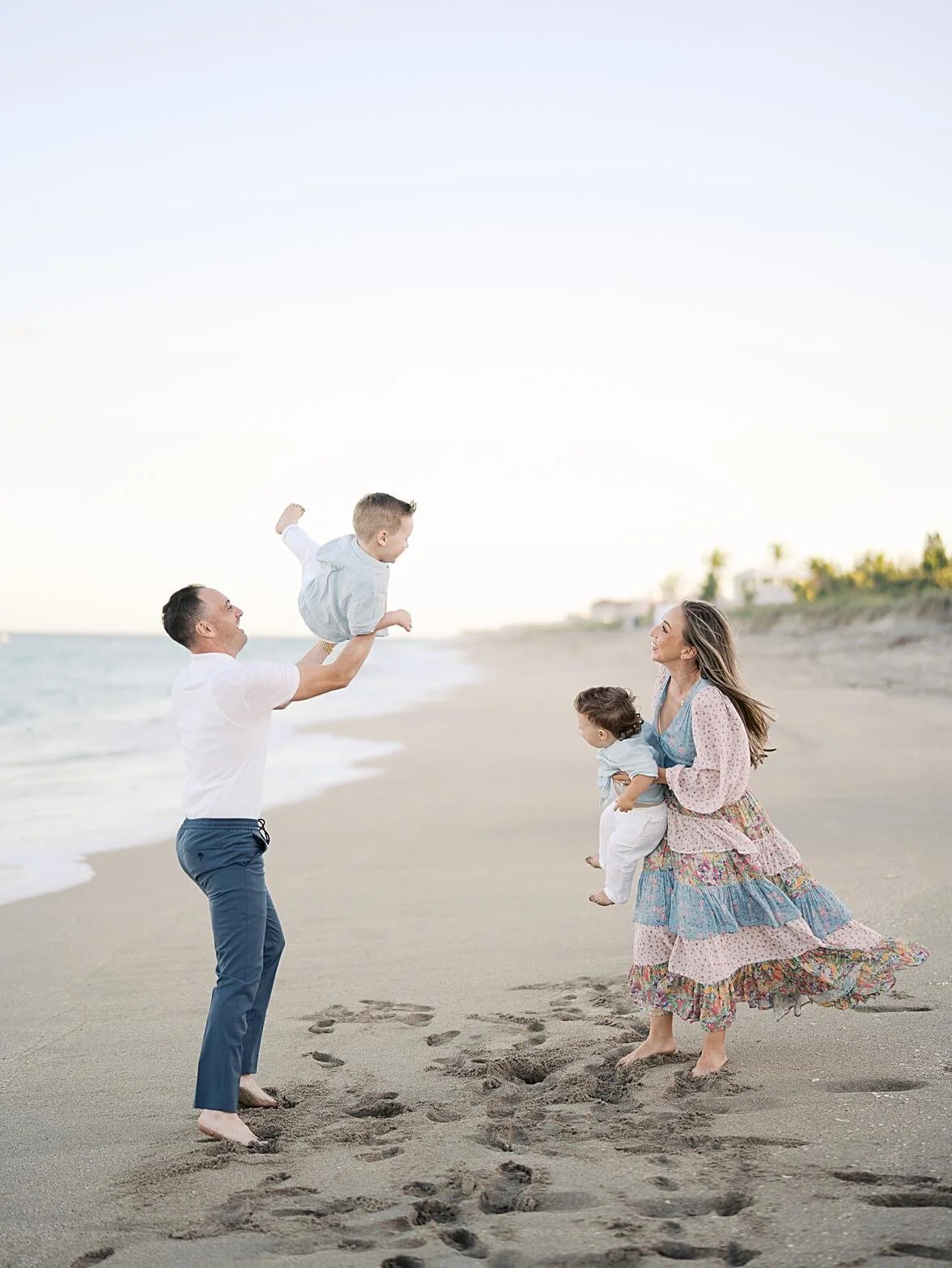 dad tossing toddler up in air while mom holds baby