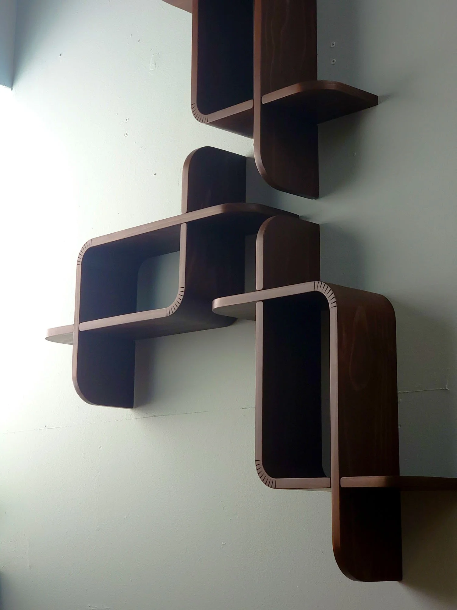 Modern wooden wall shelf with multiple compartments mounted on a light-colored wall.