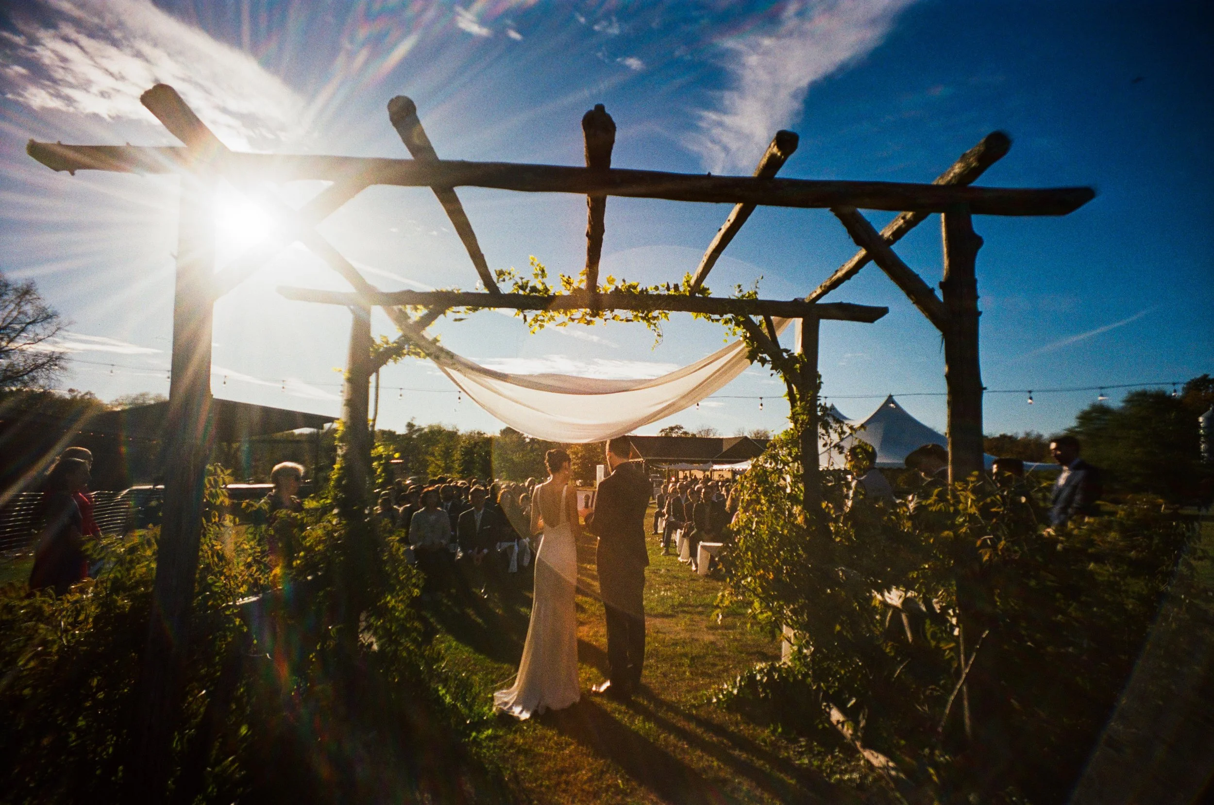 Outdoor Wedding Photography in NYC, couple getting married underneath a wood gazebo