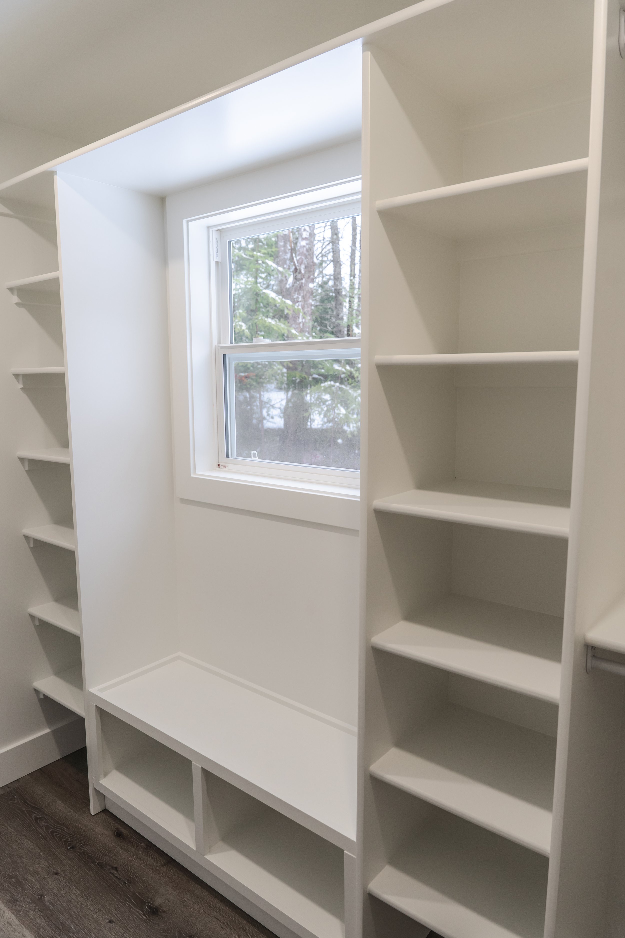White built-in shelves and a window inside a walk-in closet.