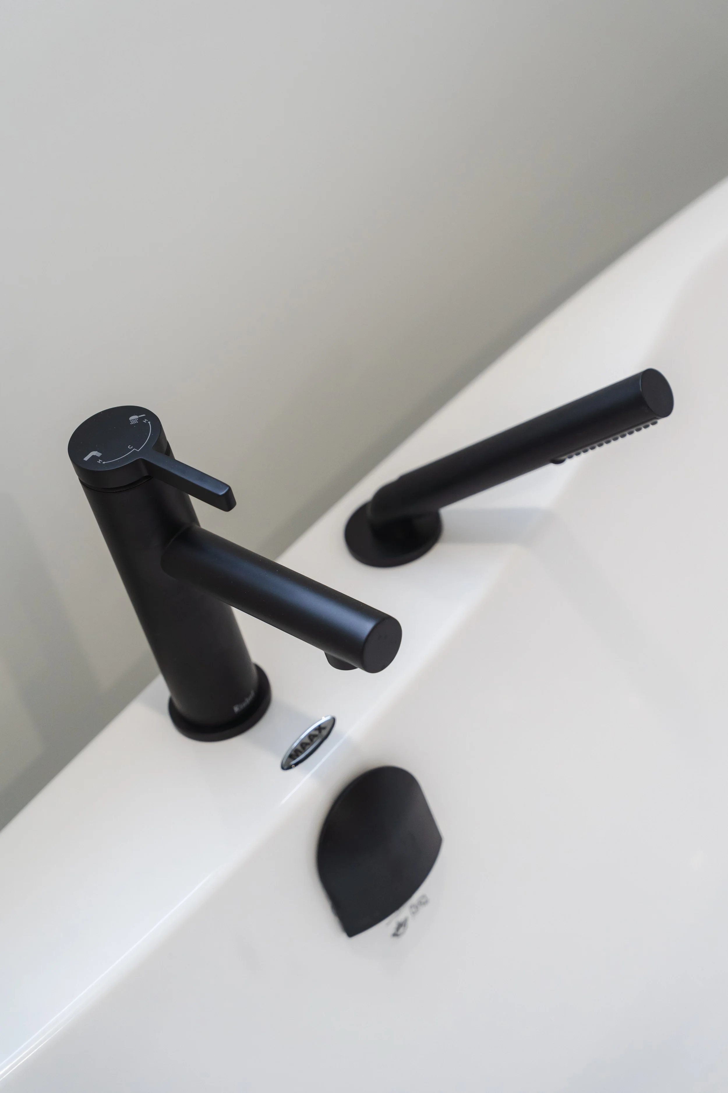 Close-up view of a modern black faucet and hand shower in a bathroom sink or bathtub area.