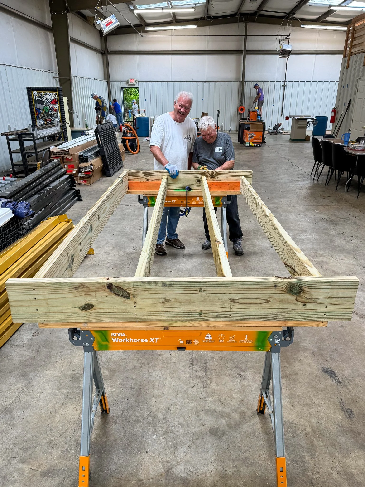  Hammer &amp; Heart volunteers build a prefab deck and accessibility ramp inside the program's new headquarters on a rainy day in May 2026. 