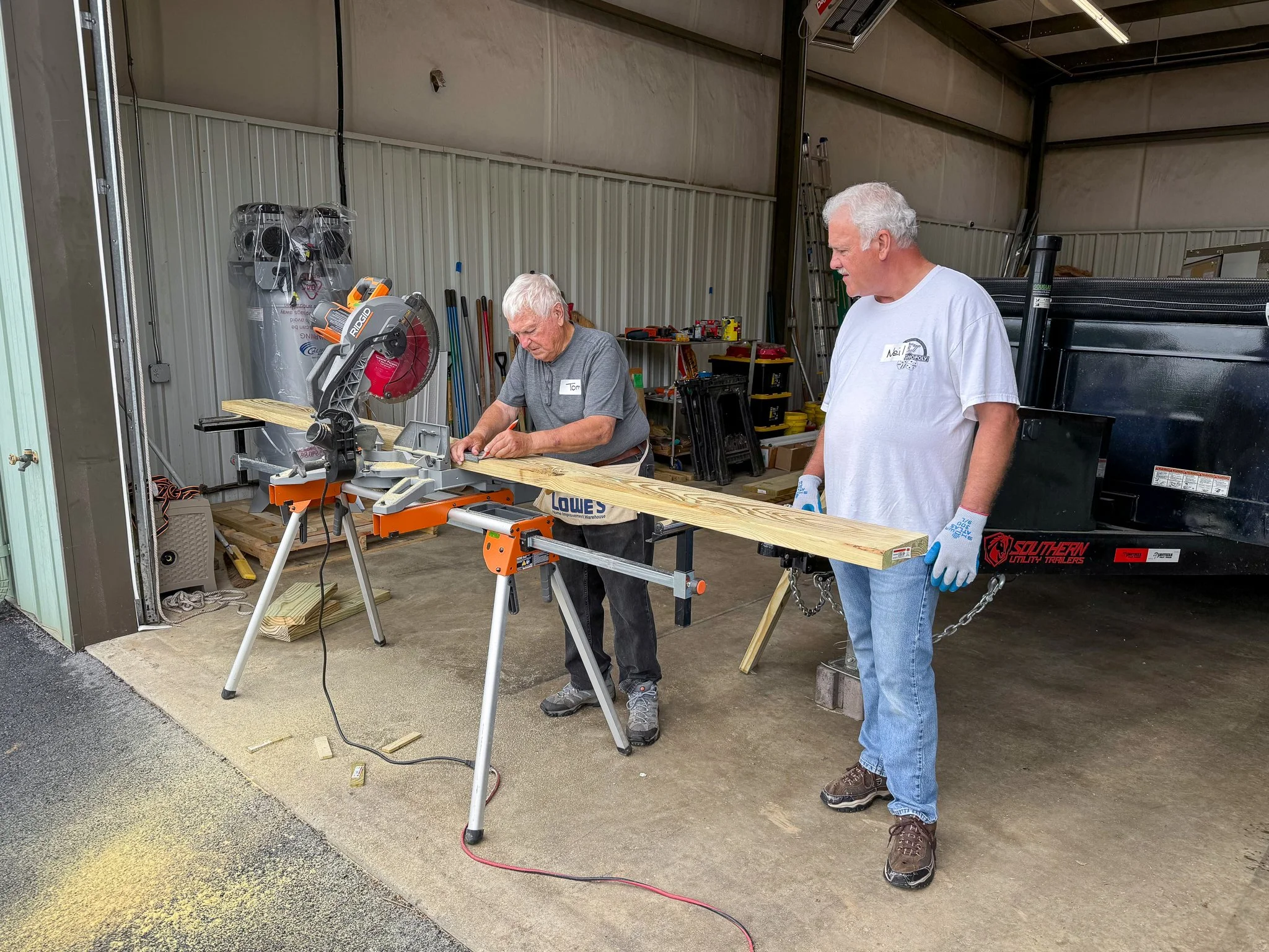  Hammer &amp; Heart volunteers build a prefab deck and accessibility ramp inside the program's new headquarters on a rainy day in May 2026. 