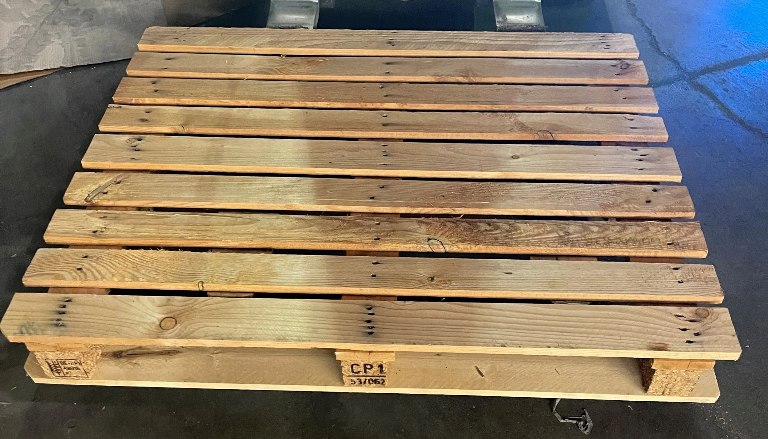 A single new wooden pallet on a concrete floor.
