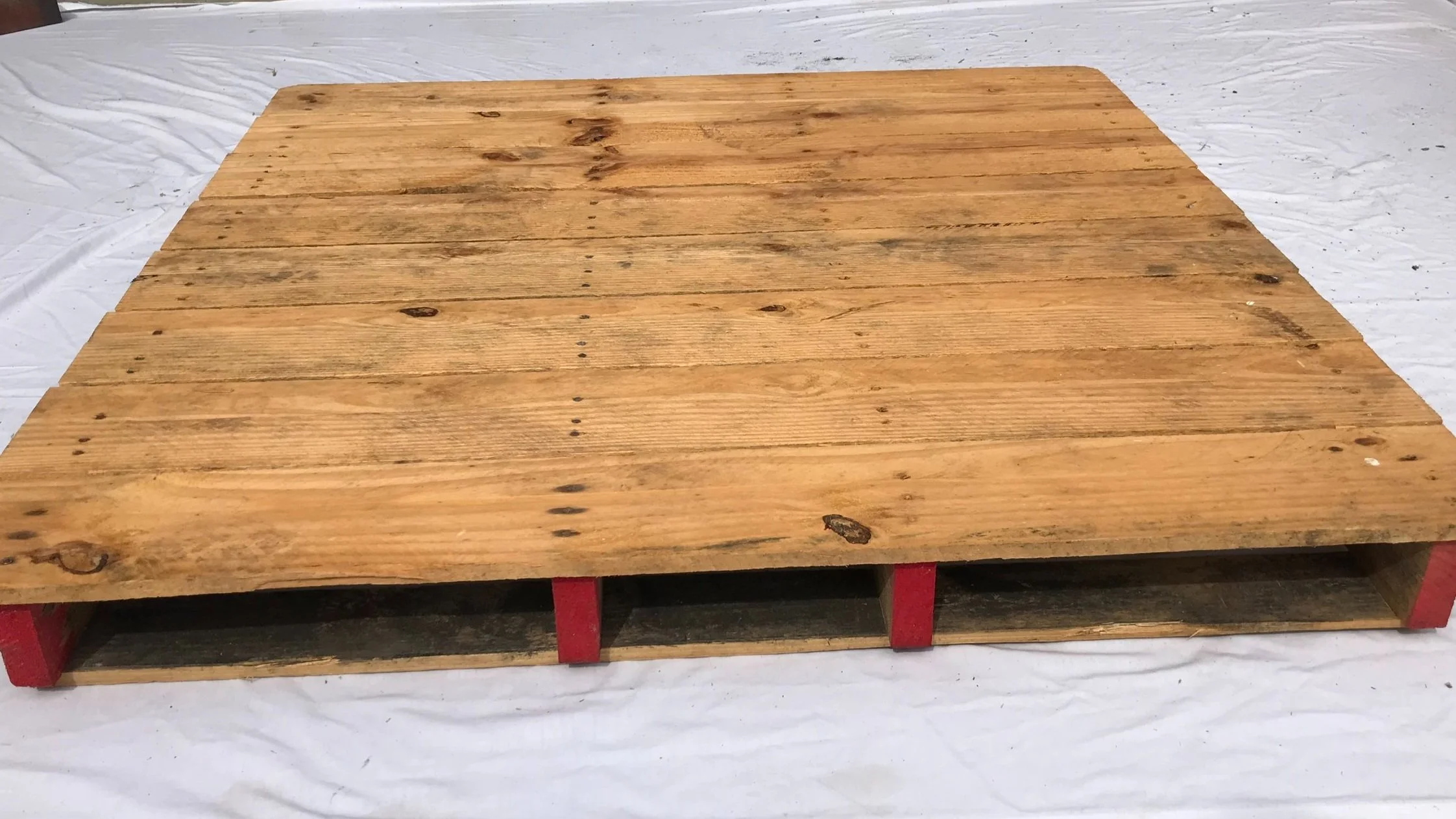 A custom made hardwood shipping pallet on display with red painted stringers illustrating the Six Sigma color coding. BEST Savannah area wood pallet distributor, BEST in the Southeast.