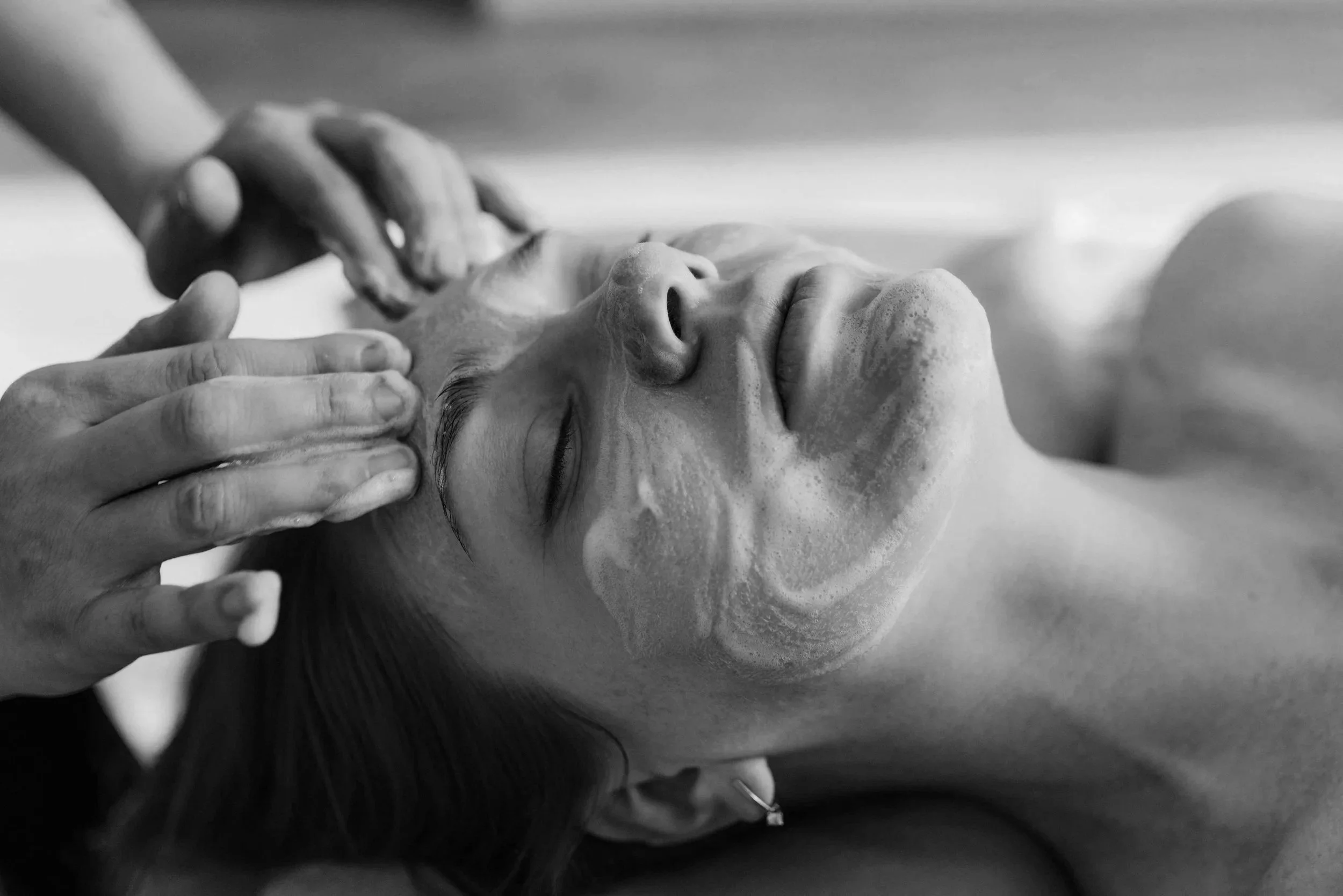 A person receiving a facial massage with their eyes closed.