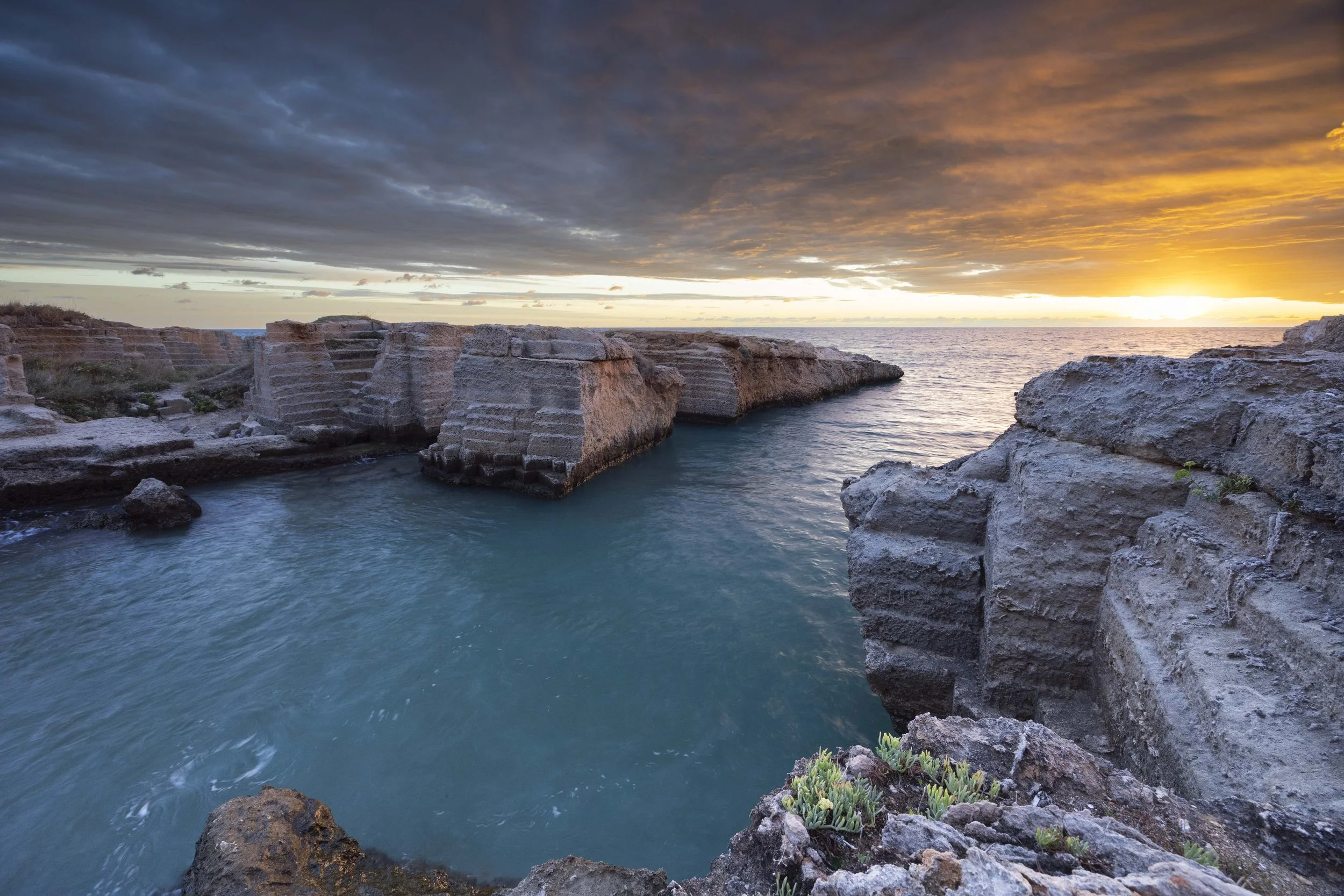 Felsen am Meer bei Sonnenaufgang, bewölkter Himmel. Fotografie.