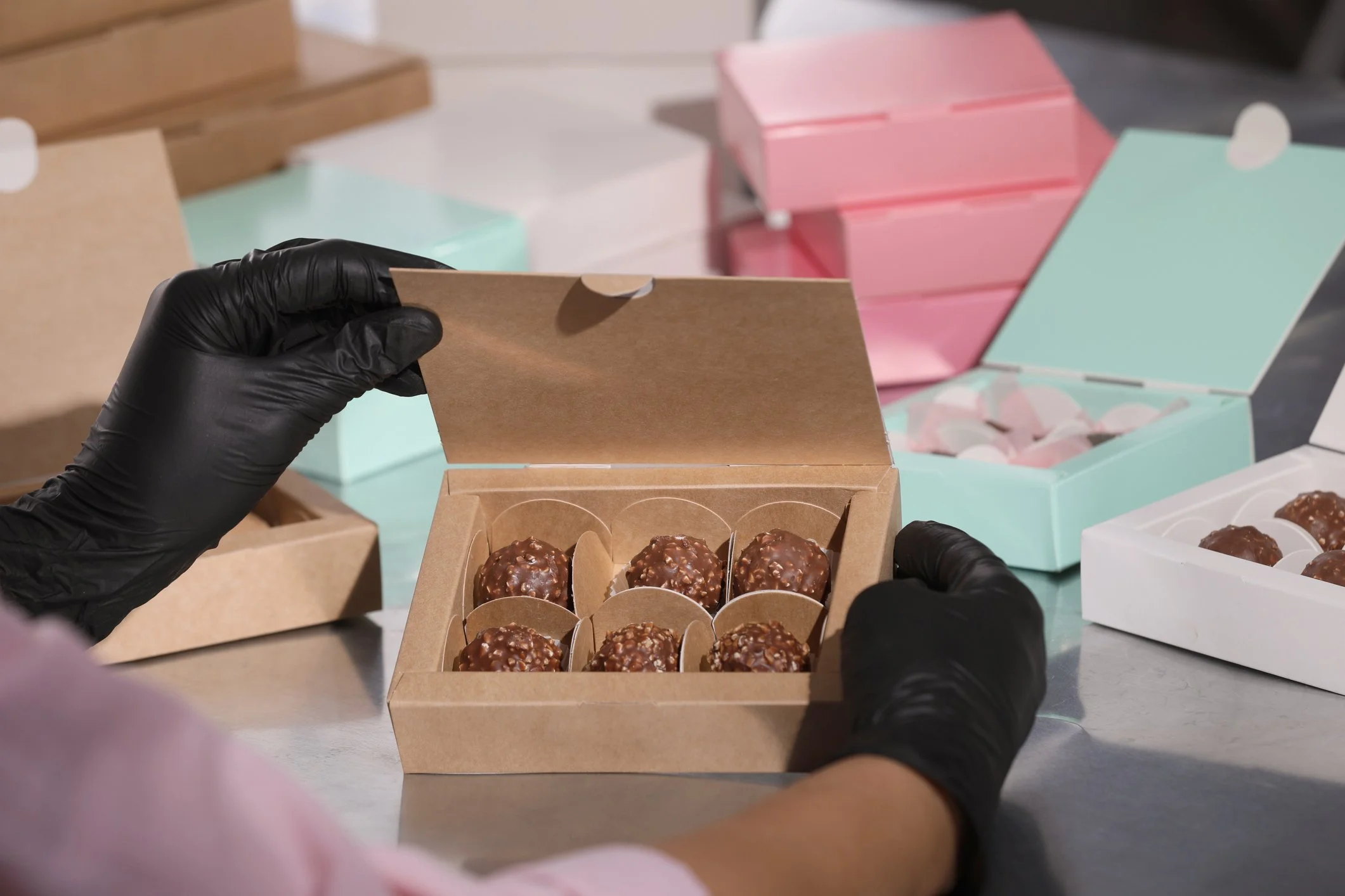 Gloved hands packing chocolates into a kraft box
