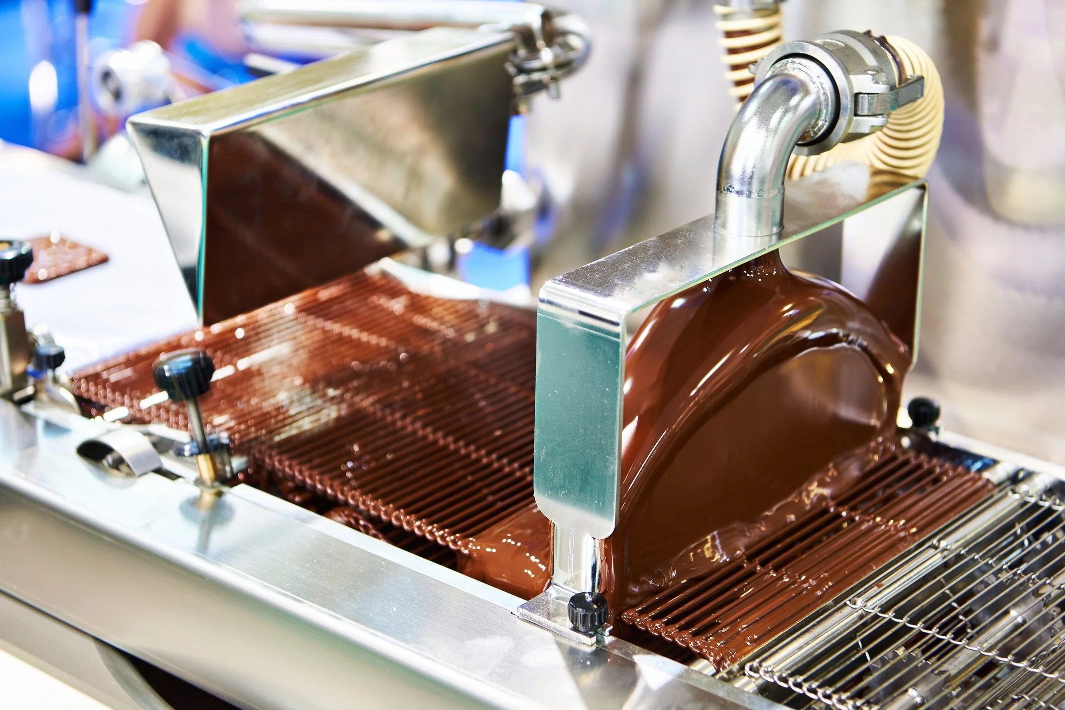 Chocolate flowing through a stainless steel tempering machine