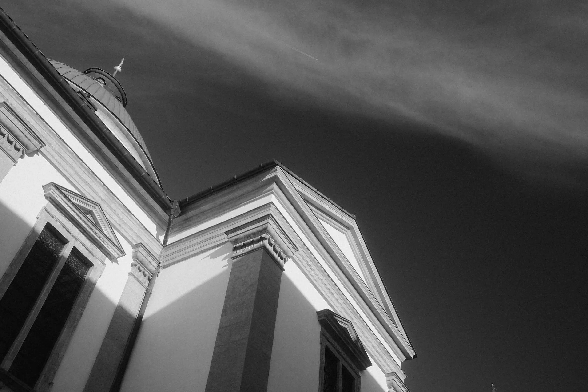 Kirchenfassade mit Barockturm und dramatischem Wolkenhimmel – analoge Ästhetik von Markus Mittermayer