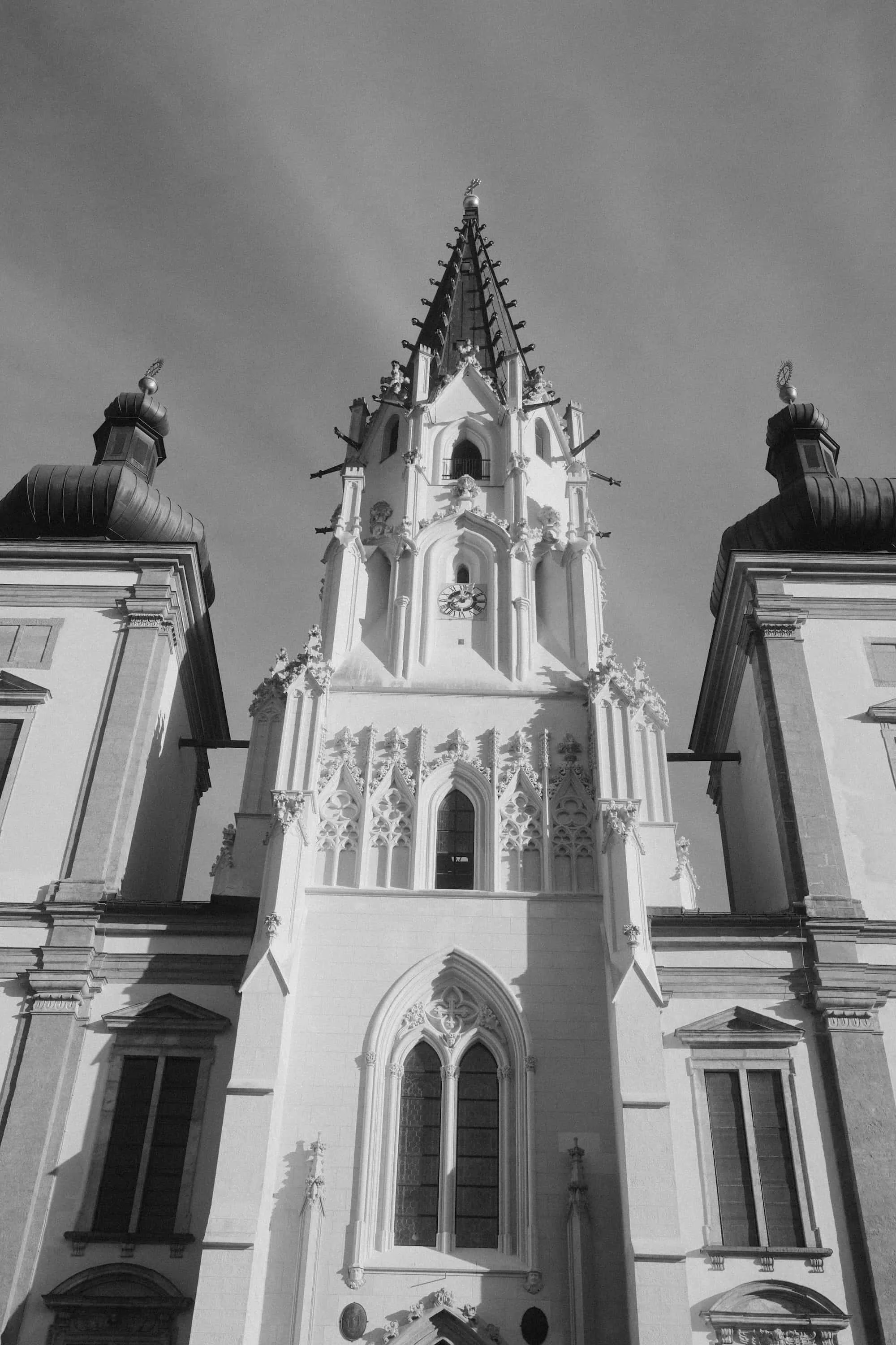 Gotische Kirchenfassade mit Uhrturm und Spitzgiebel – Fine Art Schwarz-Weiß Fotografie Niederösterreich von Markus Mittermayer