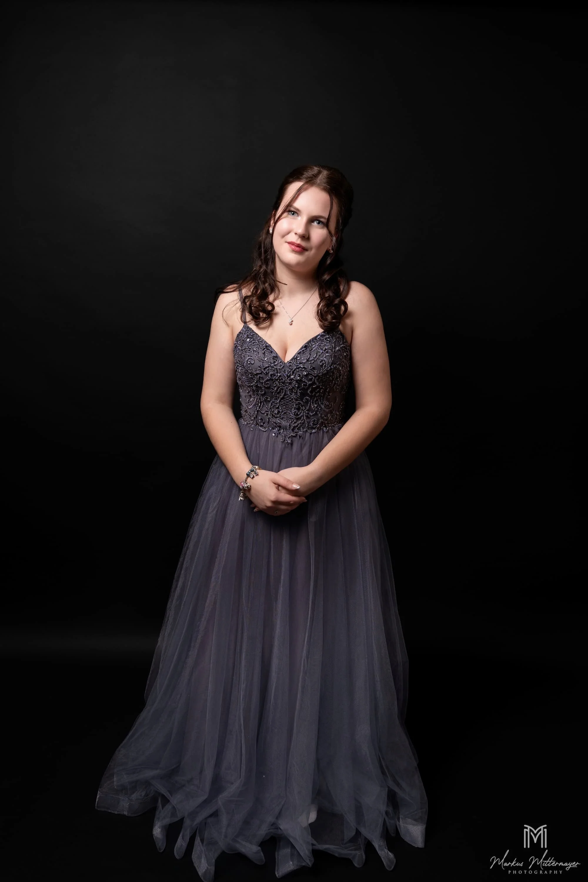 Fashion-Portrait: Frau im grauen Tüll-Kleid vor schwarzem Studiohintergrund, Schulball-Look