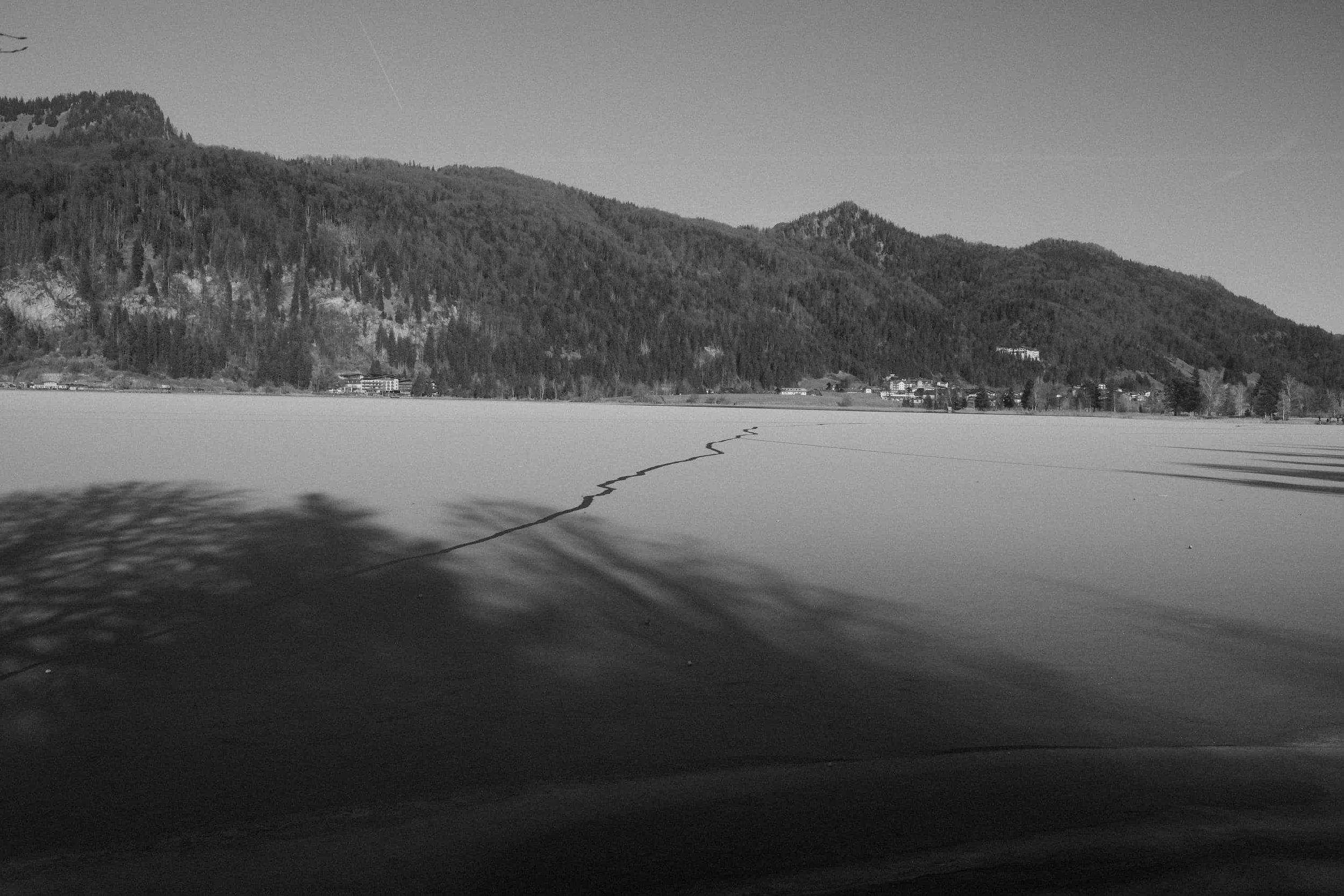 Baumschatten und Eisrisse auf zugefrorenem See – Fine Art Schwarz-Weiß Fotografie von Markus Mittermayer