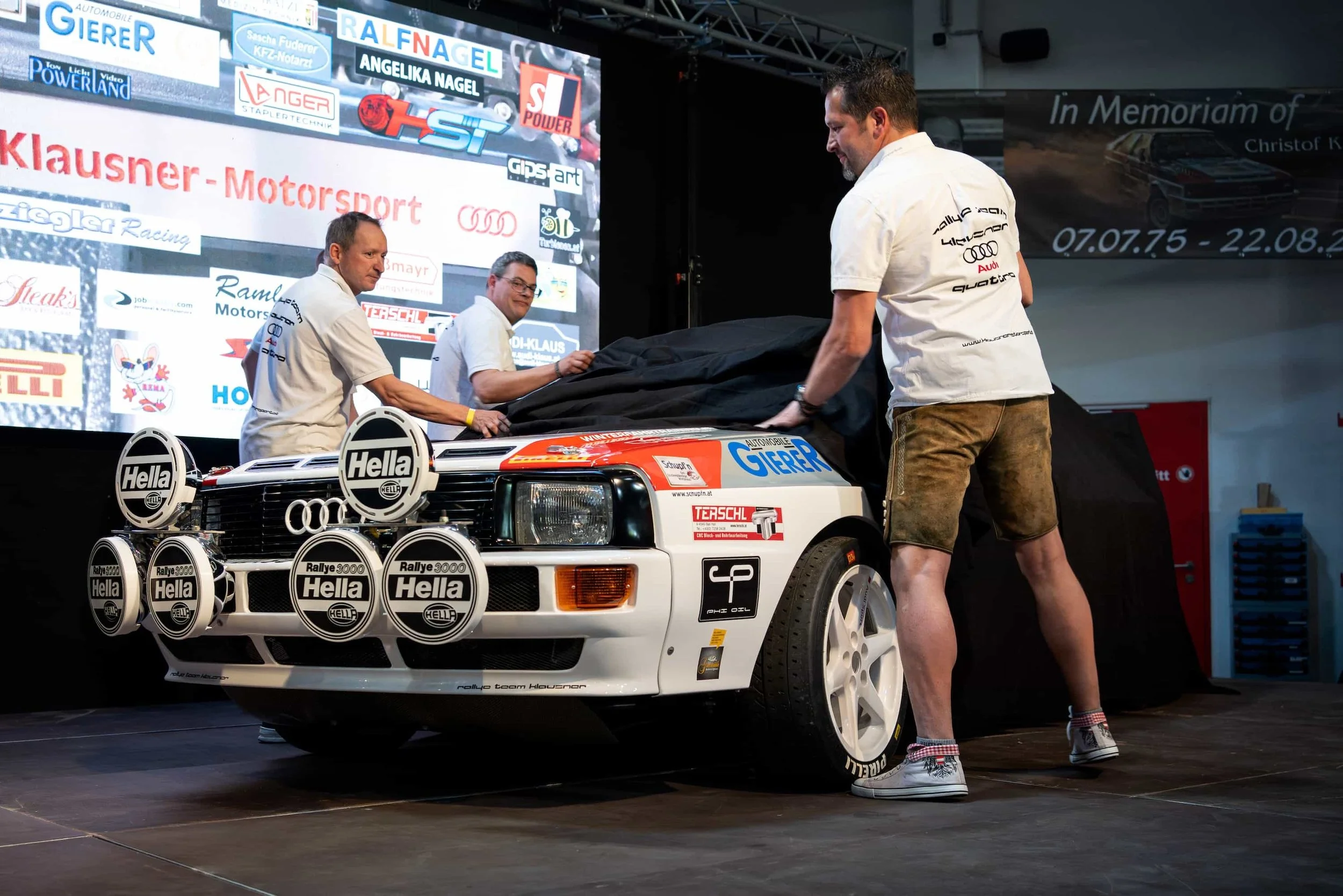 Fahrzeugpräsentation bei einem Motorsport-Event: Enthüllung eines historischen Audi Rallyefahrzeugs vor Publikum