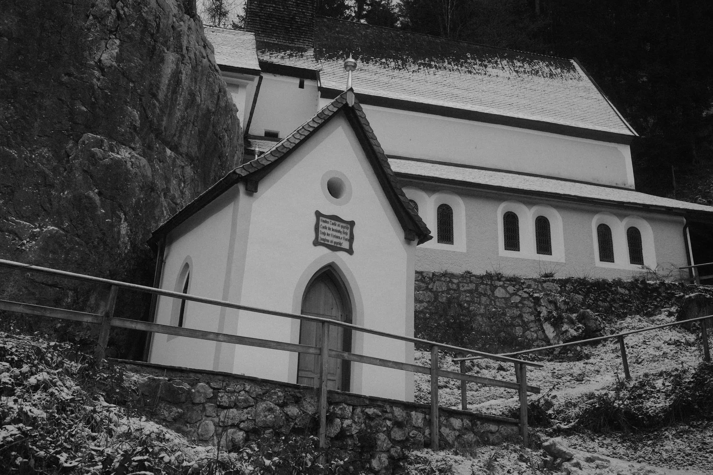 Historische Kapelle an Felswand im Schnee – Fine Art Schwarz-Weiß Fotografie von Markus Mittermayer, Österreich
