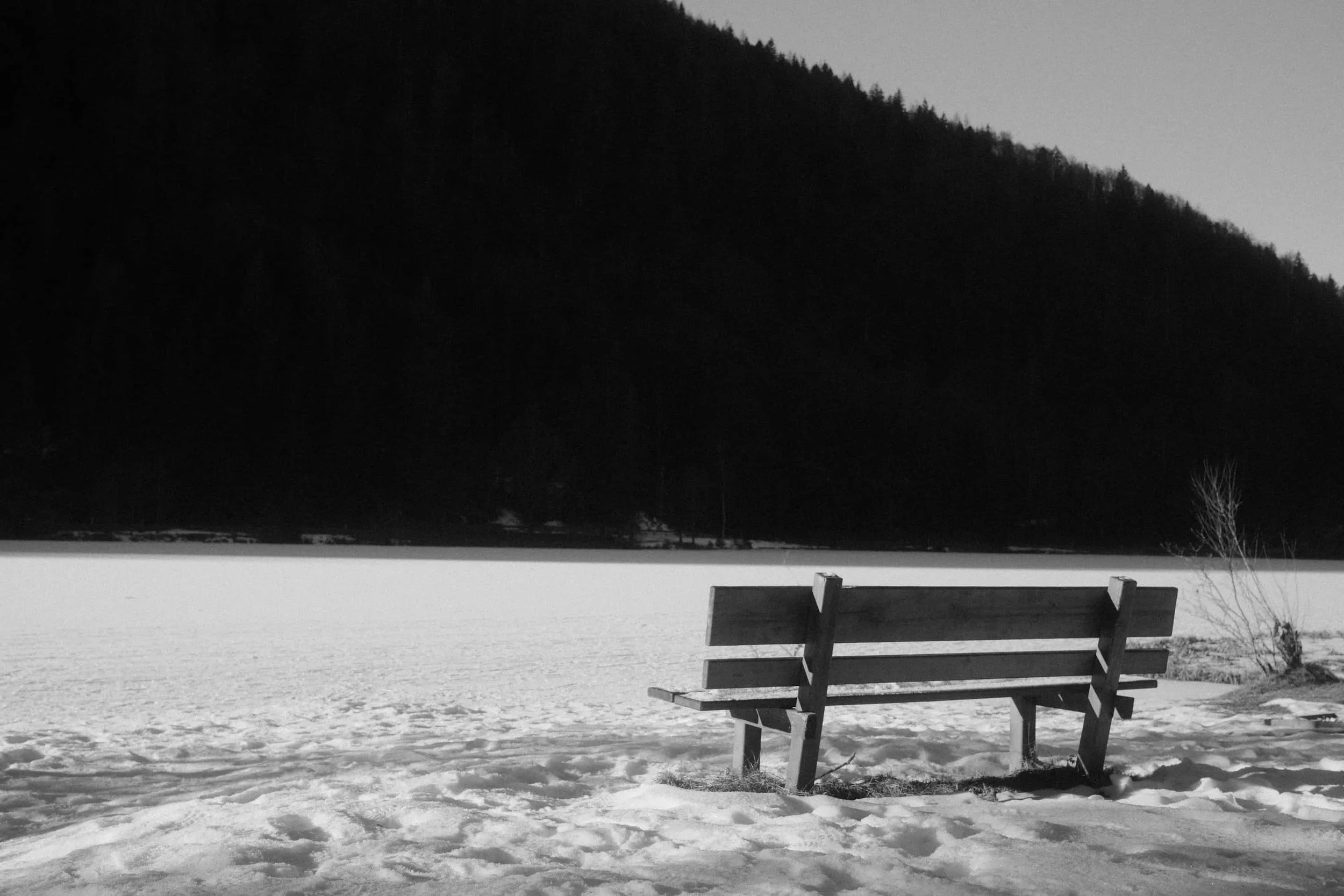 Leere Bank vor zugefrorenem See im Winter – Schwarz-Weiß Fine Art Fotografie von Markus Mittermayer, Österreich