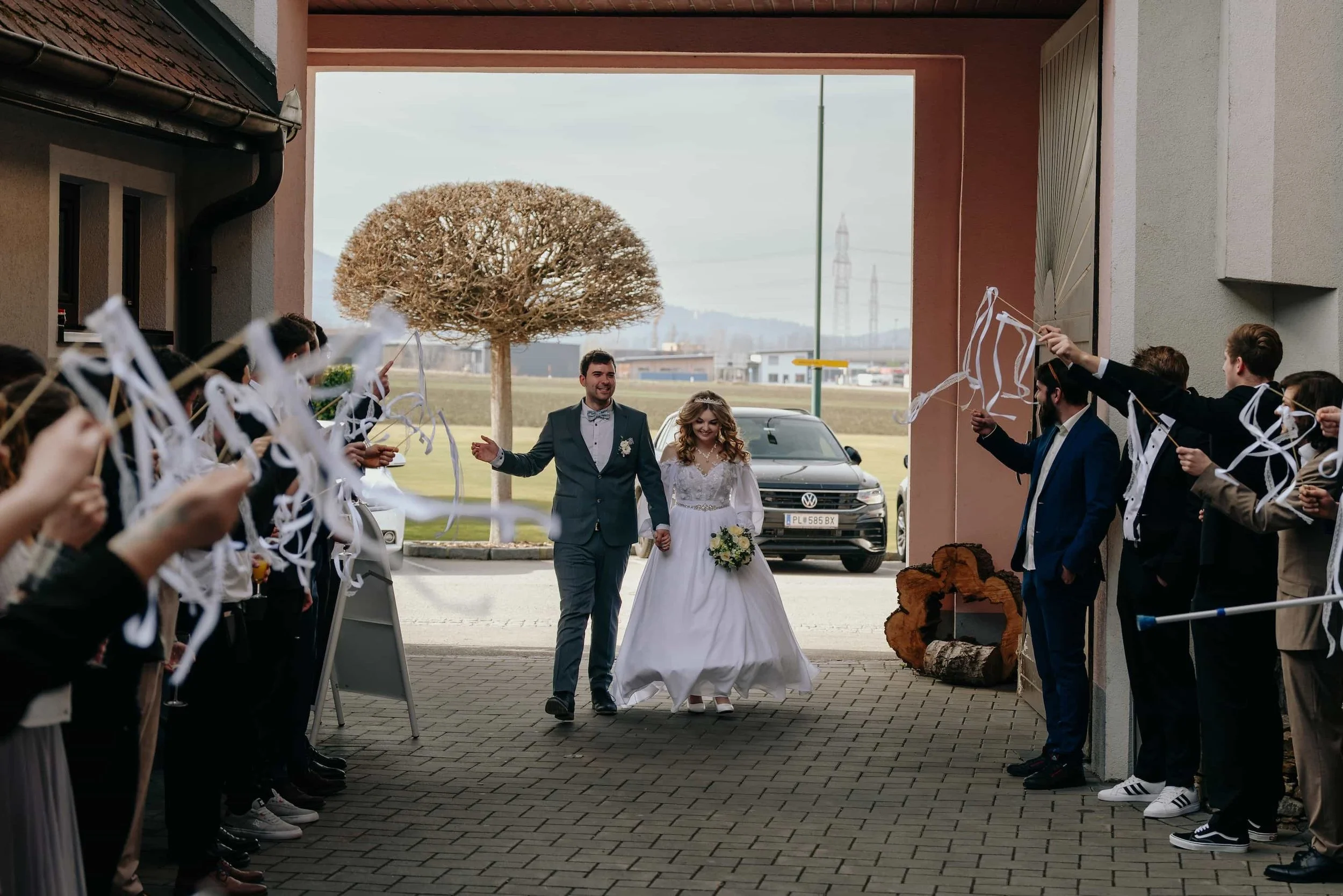 Brautpaar zieht strahlend durch ein Spalier mit weißen Bändern nach der Hochzeitsfeier in Niederösterreich beim Birgl in Hürm