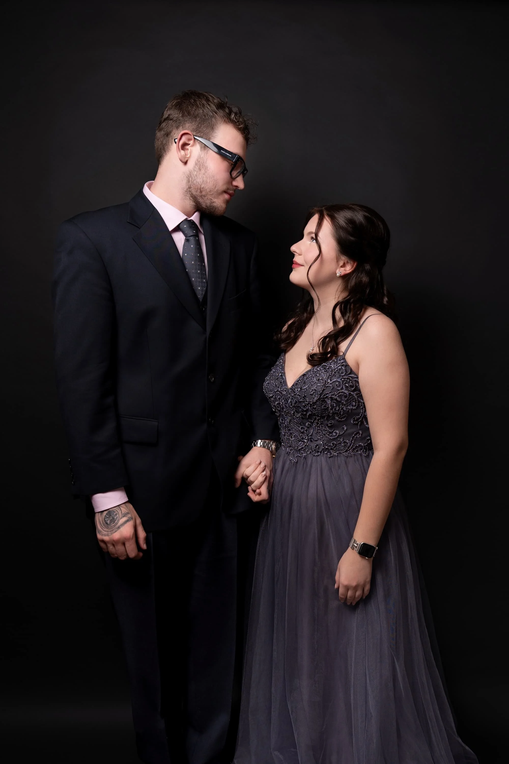 Paar-Portrait: Frau im grauen Tüll-Kleid und Mann im schwarzem Anzug vor dunklem Hintergrund