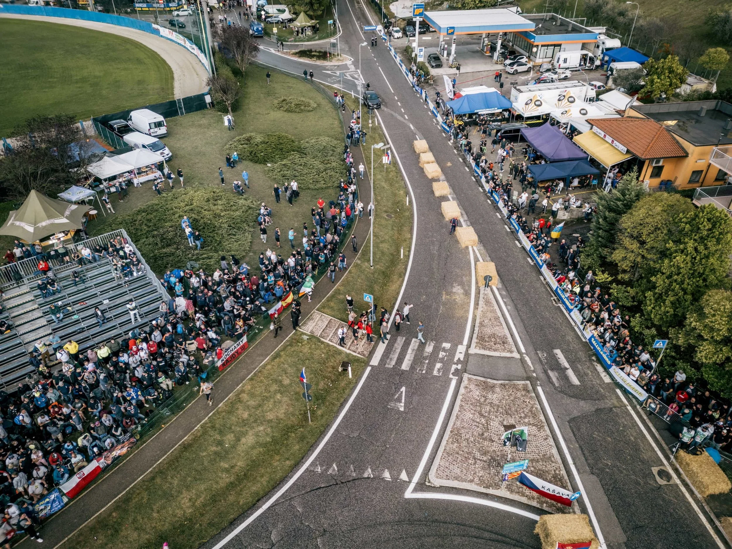 Luftaufnahme einer Rennstrecken-Kurve mit Zuschauern, Tribünen und Eventzelten bei einem Motorsport-Event in San Marino.