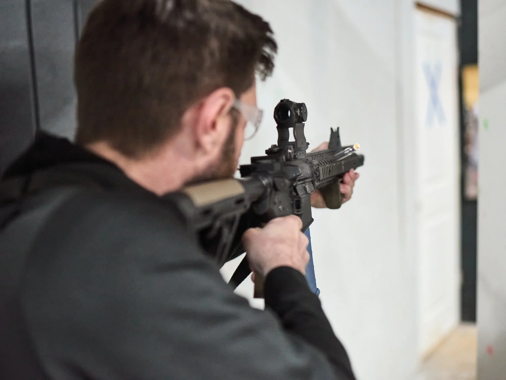 Man aiming a rifle indoors.