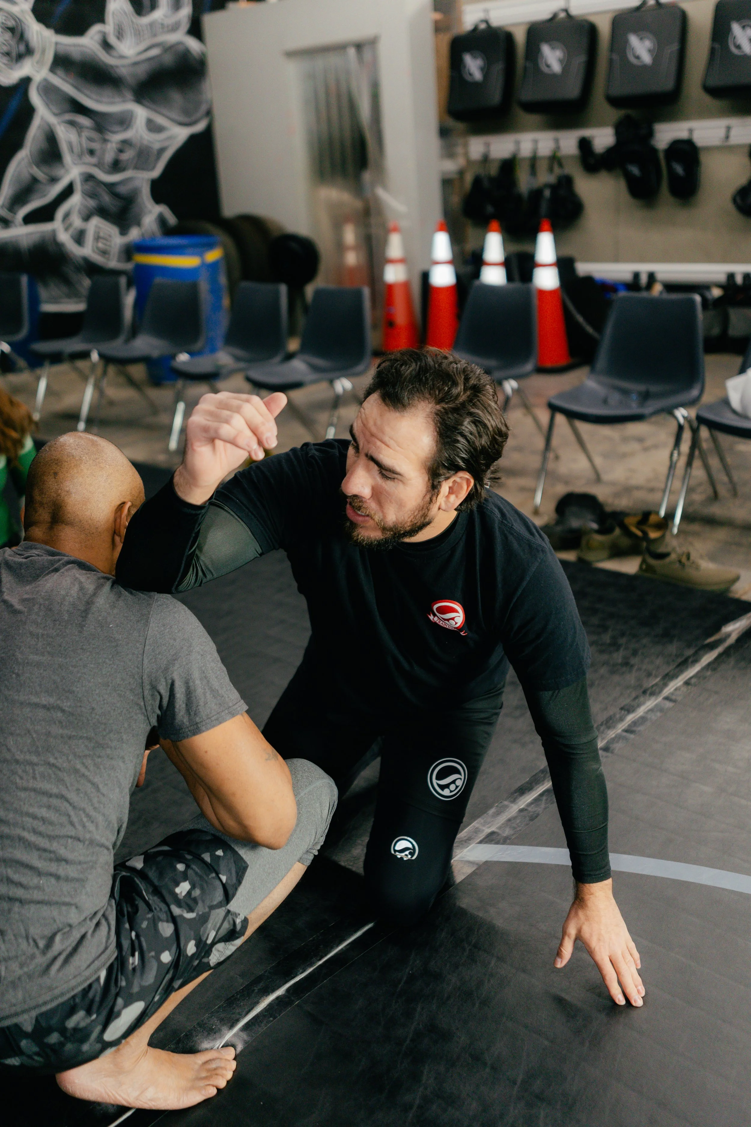 Two men engaged in a grappling training session in a martial arts gym.