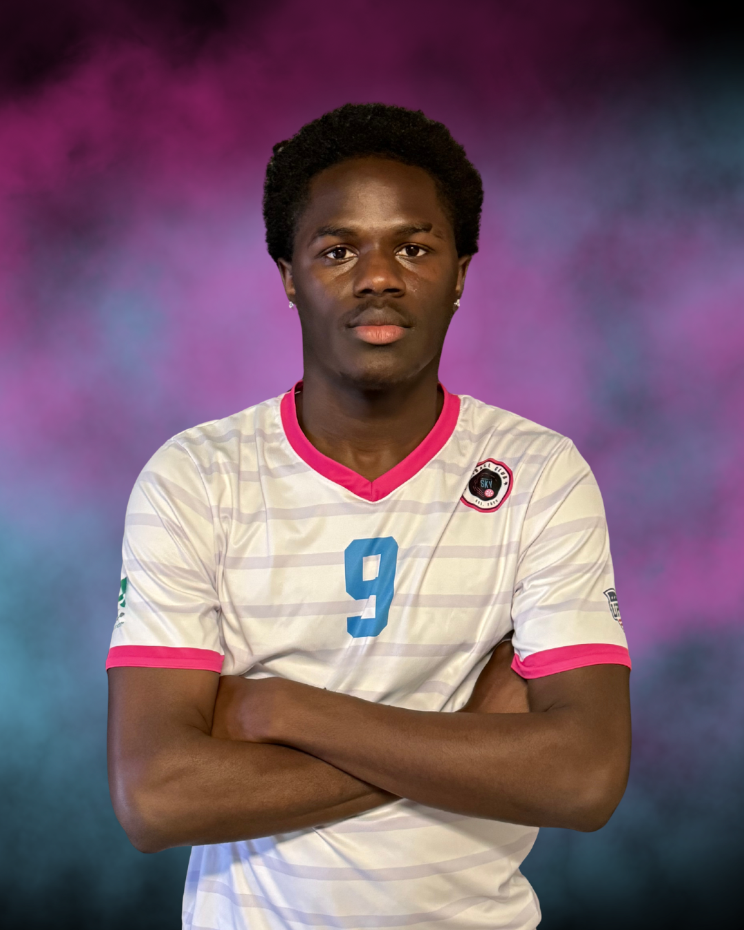 A young man in a black and blue sports jersey with the number 31, standing outdoors with a pink and gray cloudy background.