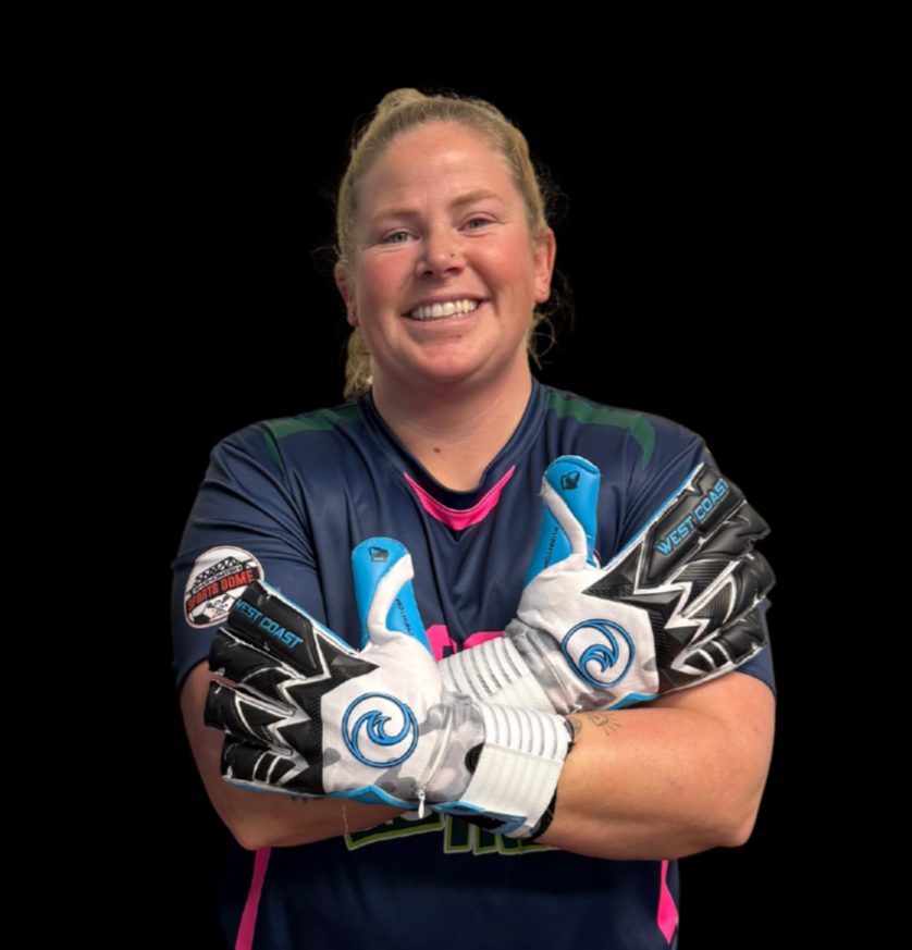 A woman with a ponytail hairstyle, smiling, wearing a sports jersey with various logos including 'Big Trees' and 'DIAZA,' standing against a colorful, artistic background.