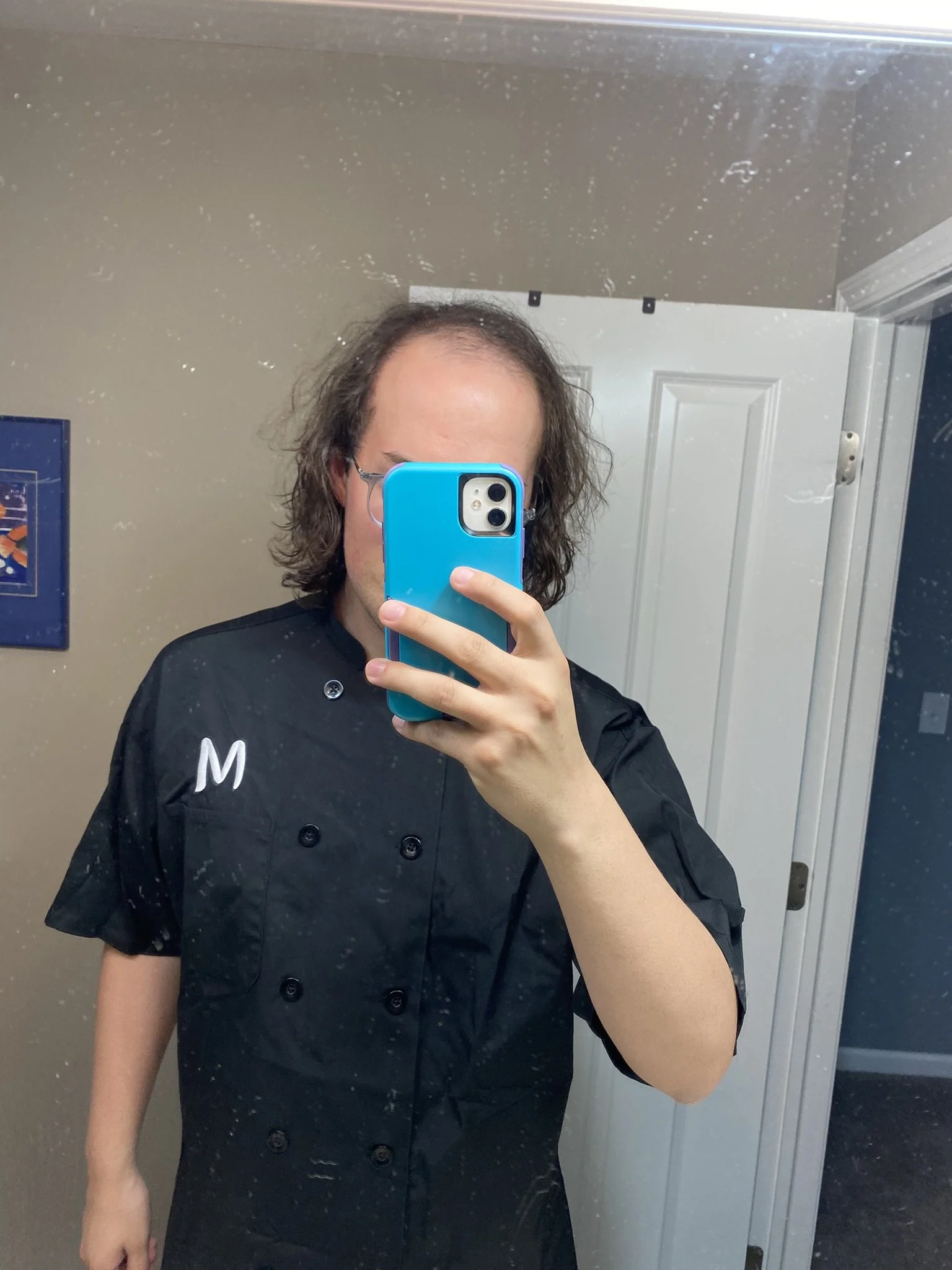 Image is a photo of Lee taking a selfie. Their phone is covering their face.