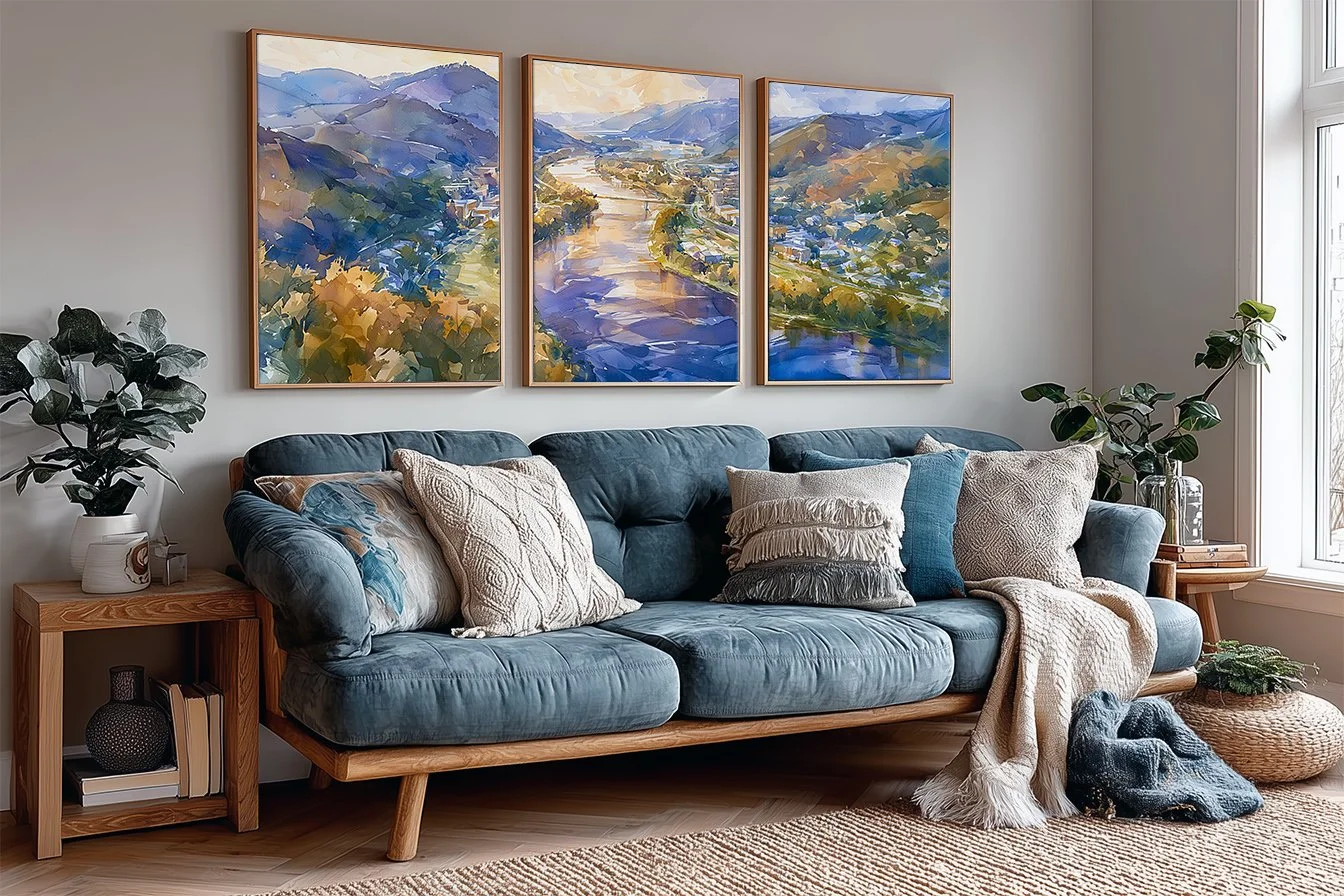 Three-panel Wisconsin river valley watercolor wall art above a blue sofa in a living room