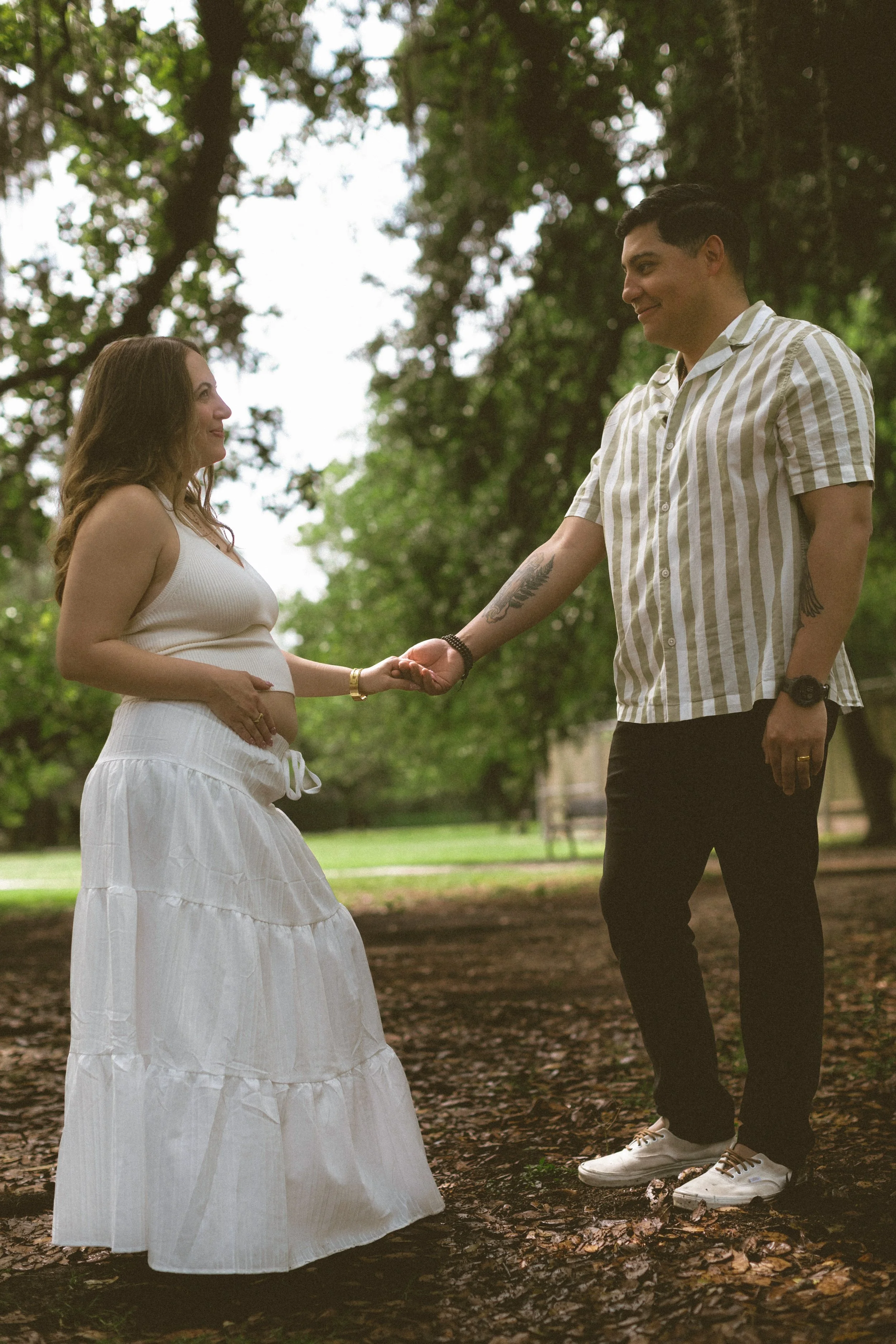Mother smiling beneath oak trees during an Audubon Park maternity session.
