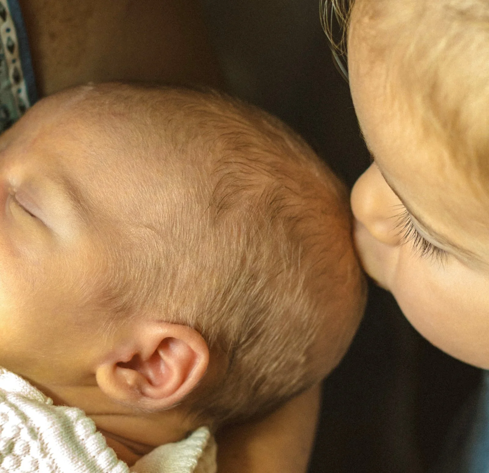 Close-up of a sibling and newborn during an intimate family photography session.