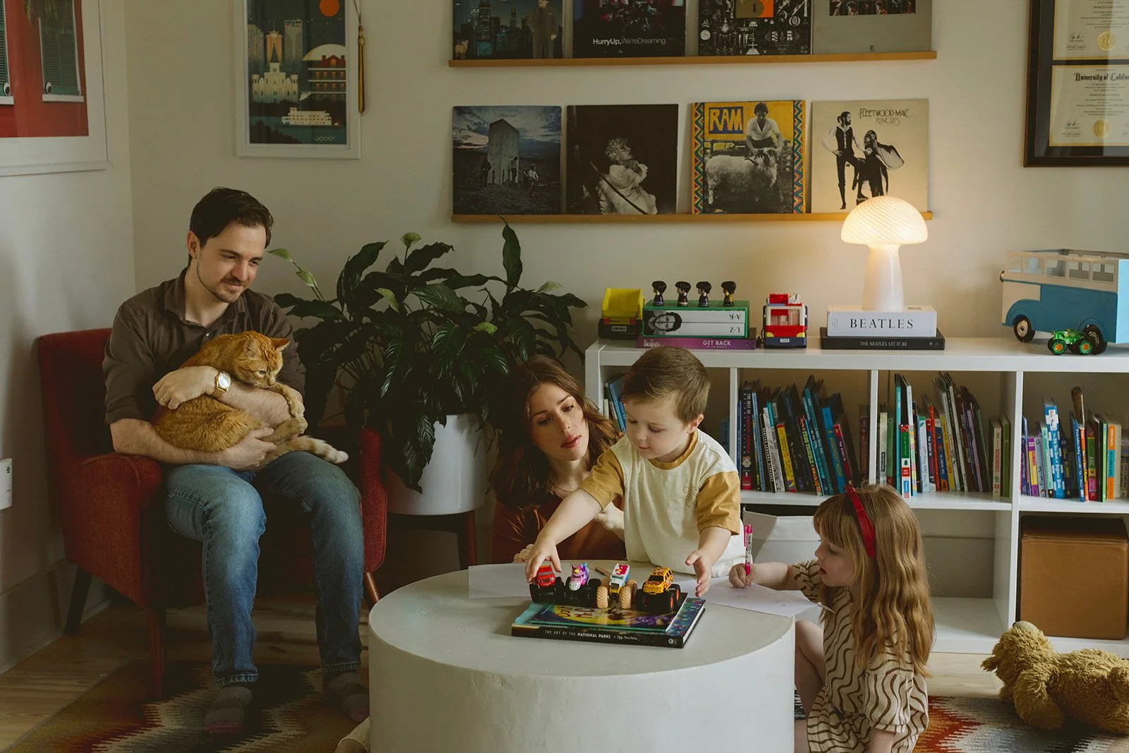 New Orleans lifestyle family photographer with dad holding beloved family cat in red chair during in-home session.