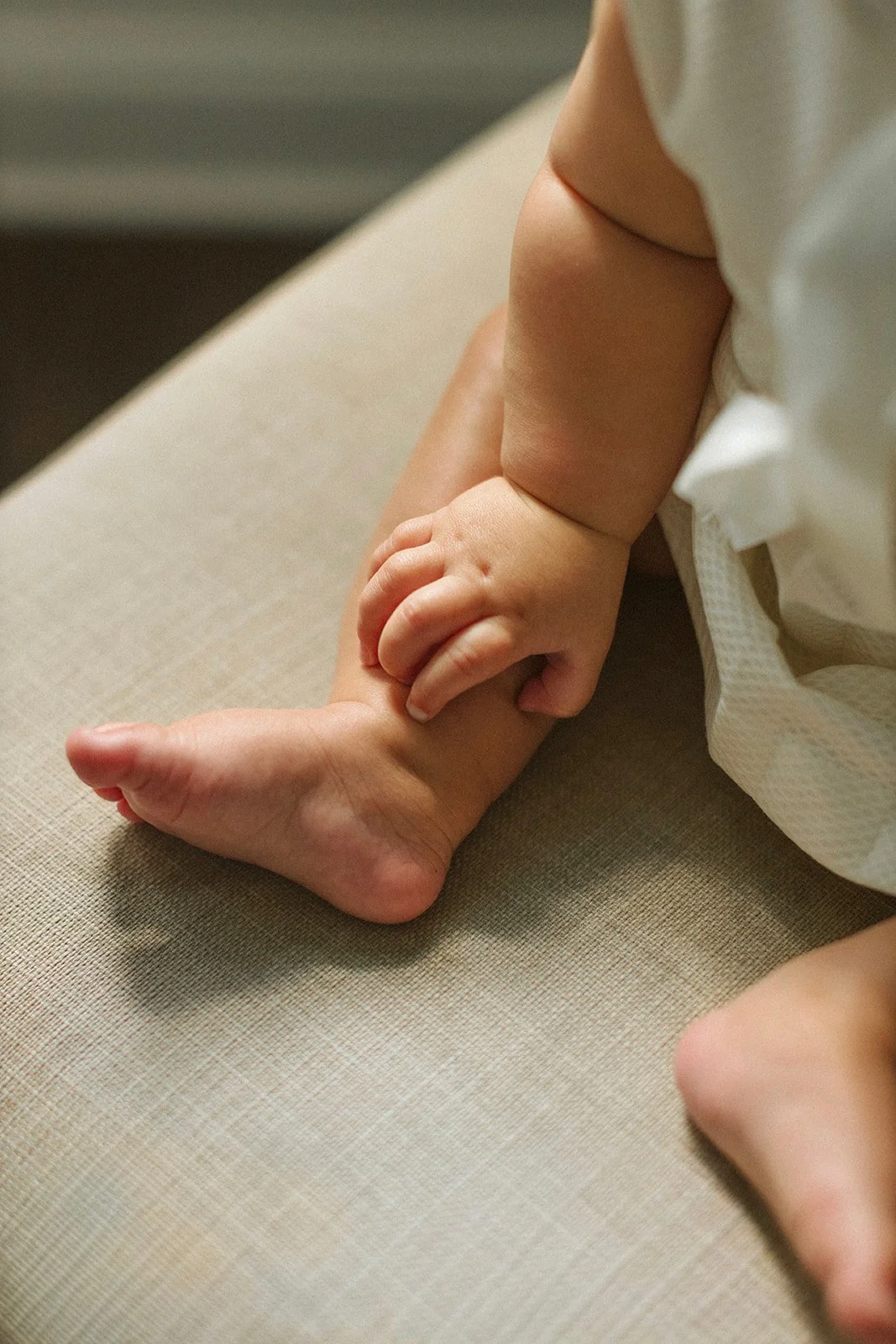 Close-up of a baby's hands and feet photographed in natural window light at home.