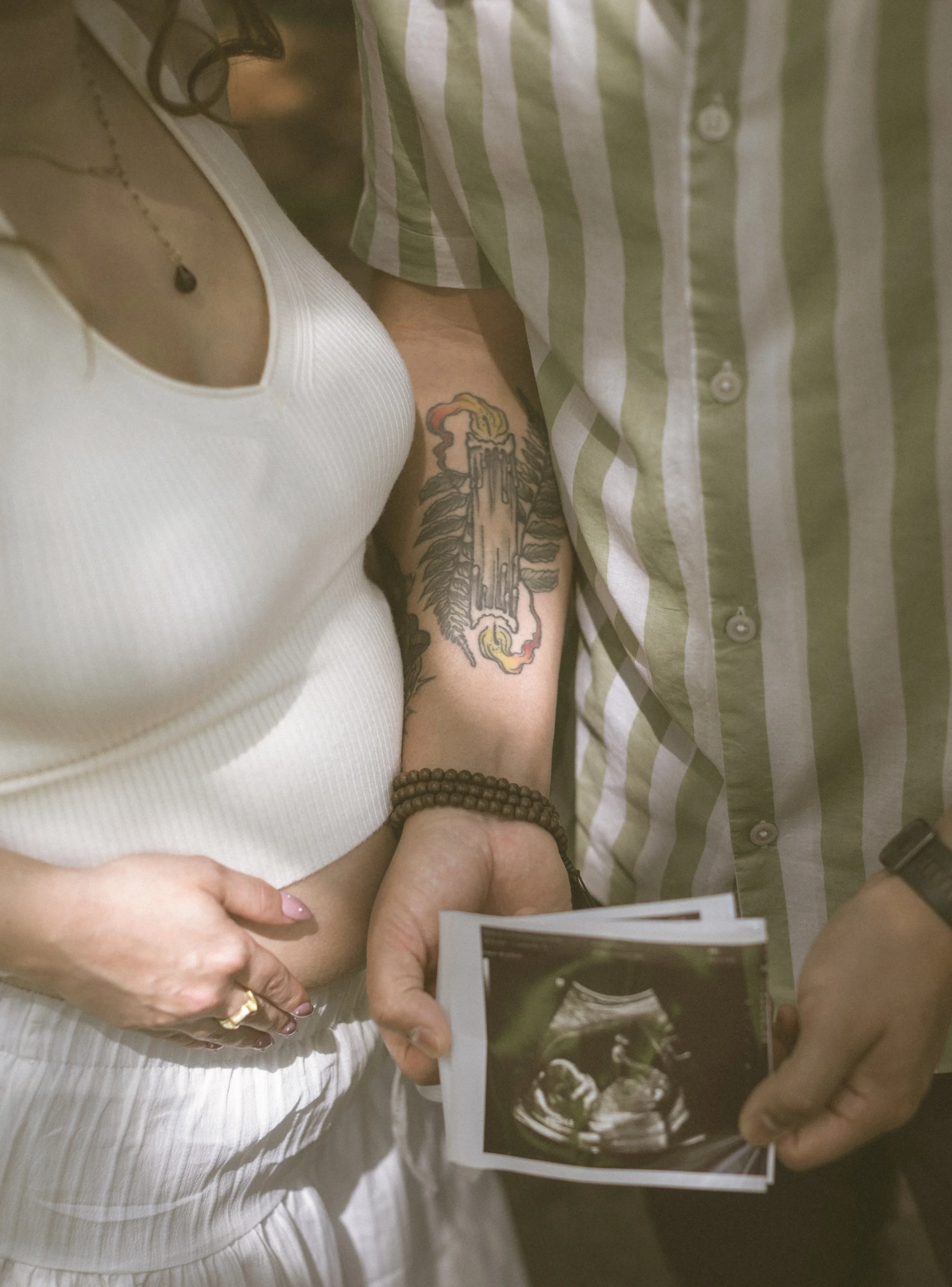 Close-up maternity detail photograph with hands resting on baby bump.